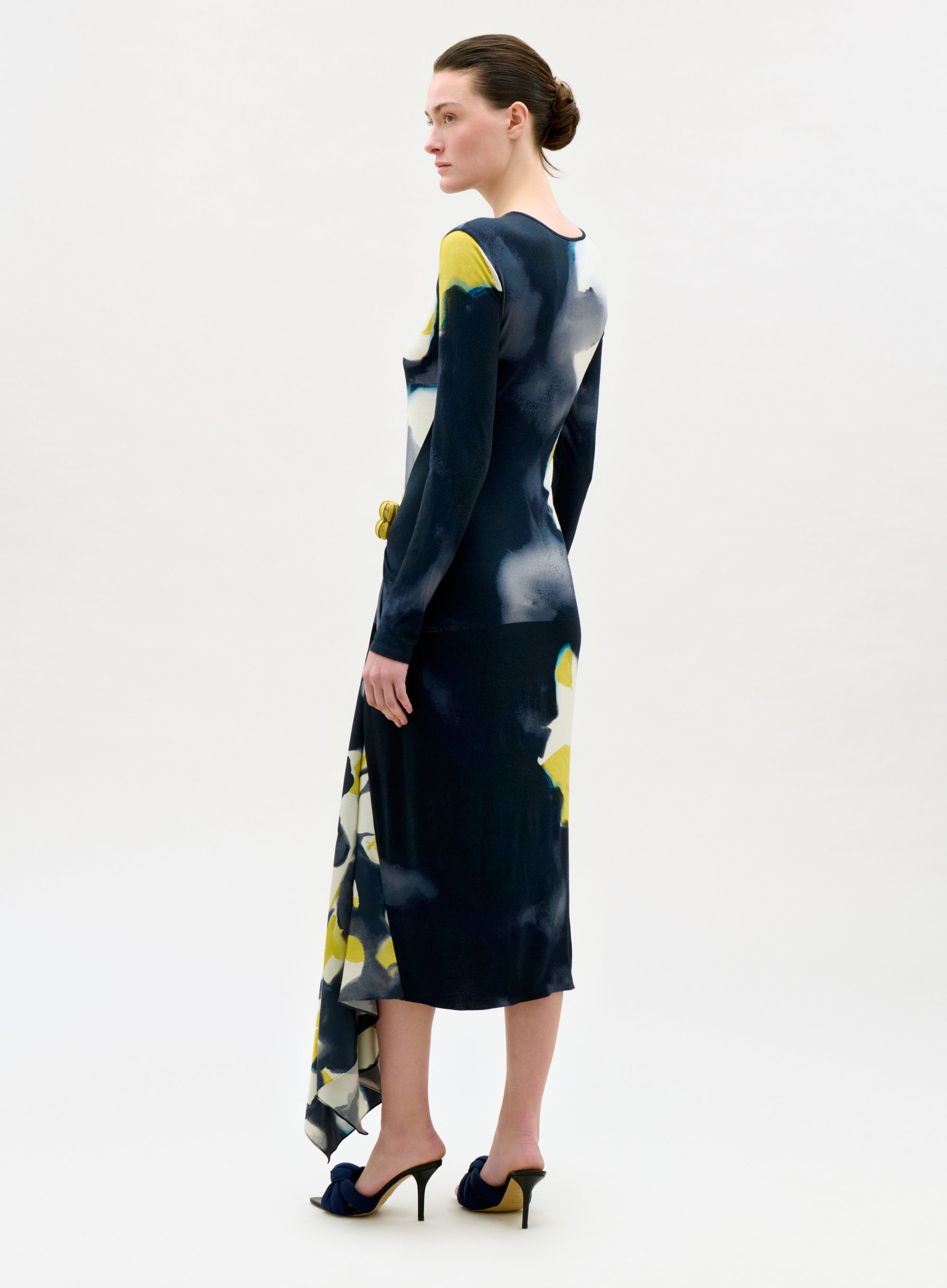Woman wearing a black dress with yellow floral patterns on a white background