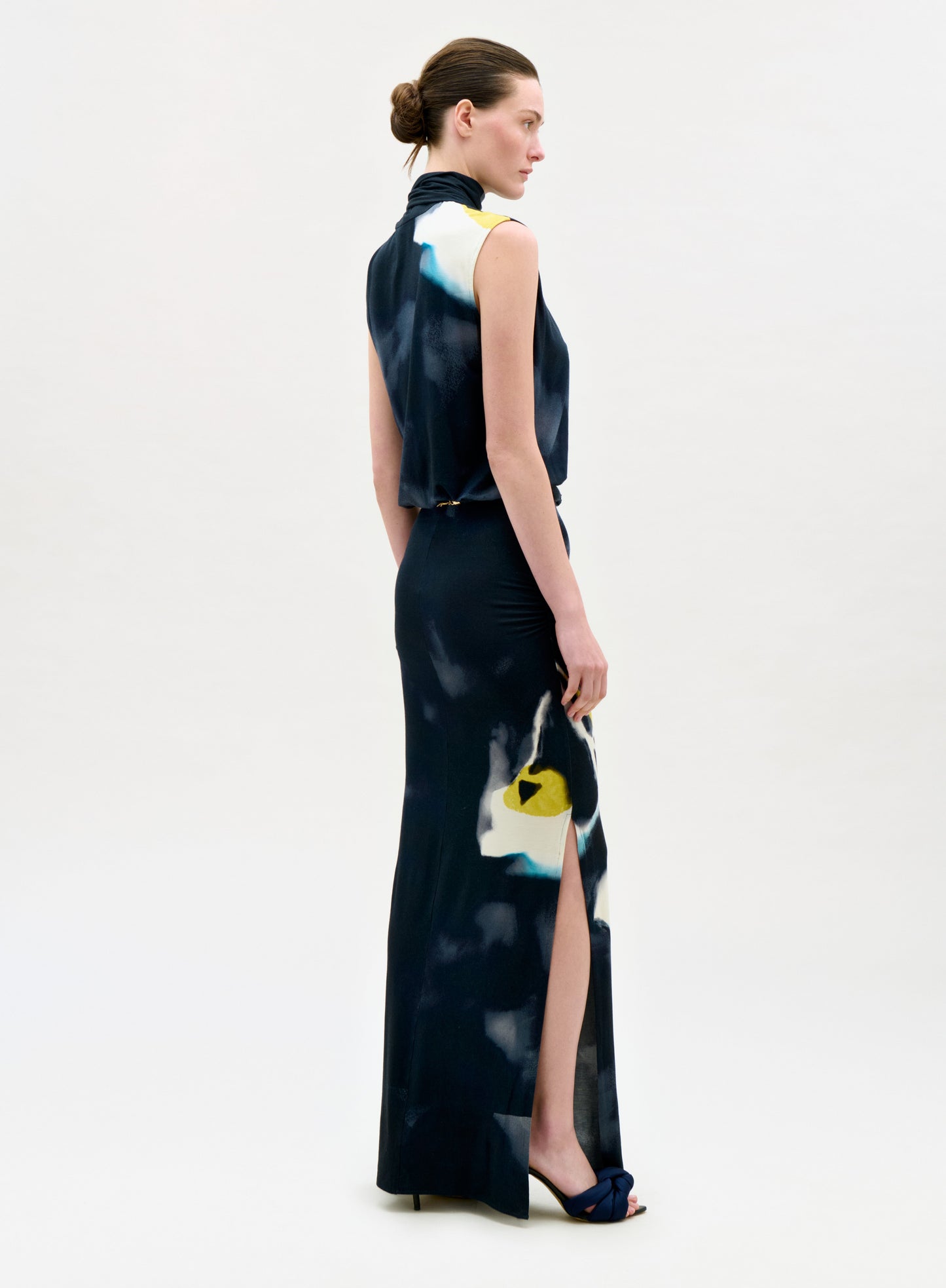 Woman wearing a long, dark-colored dress with abstract patterns on a white background