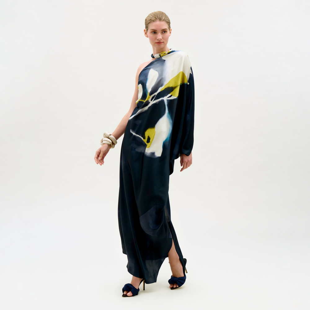 Woman wearing a long, dark blue dress with abstract white and yellow patterns on a white background