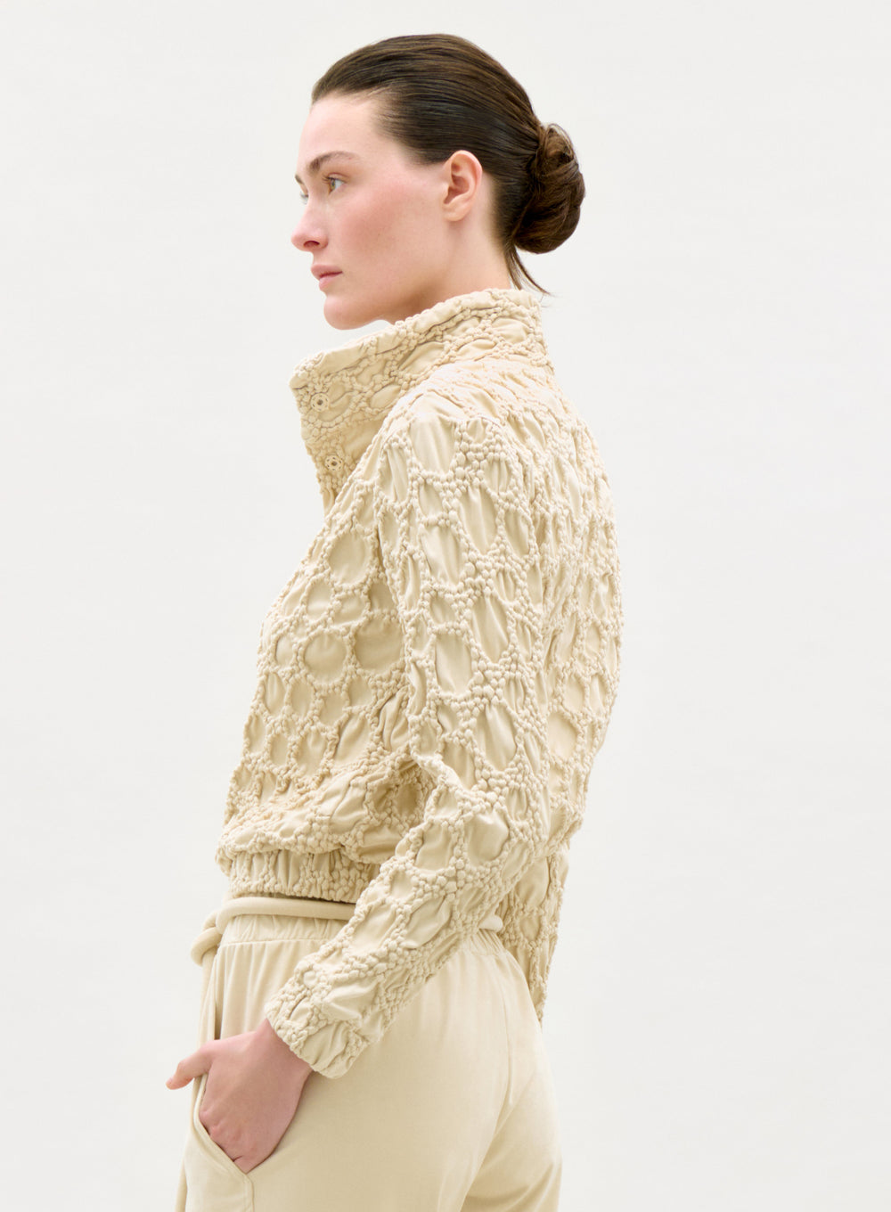Woman wearing a textured beige jacket on a white background