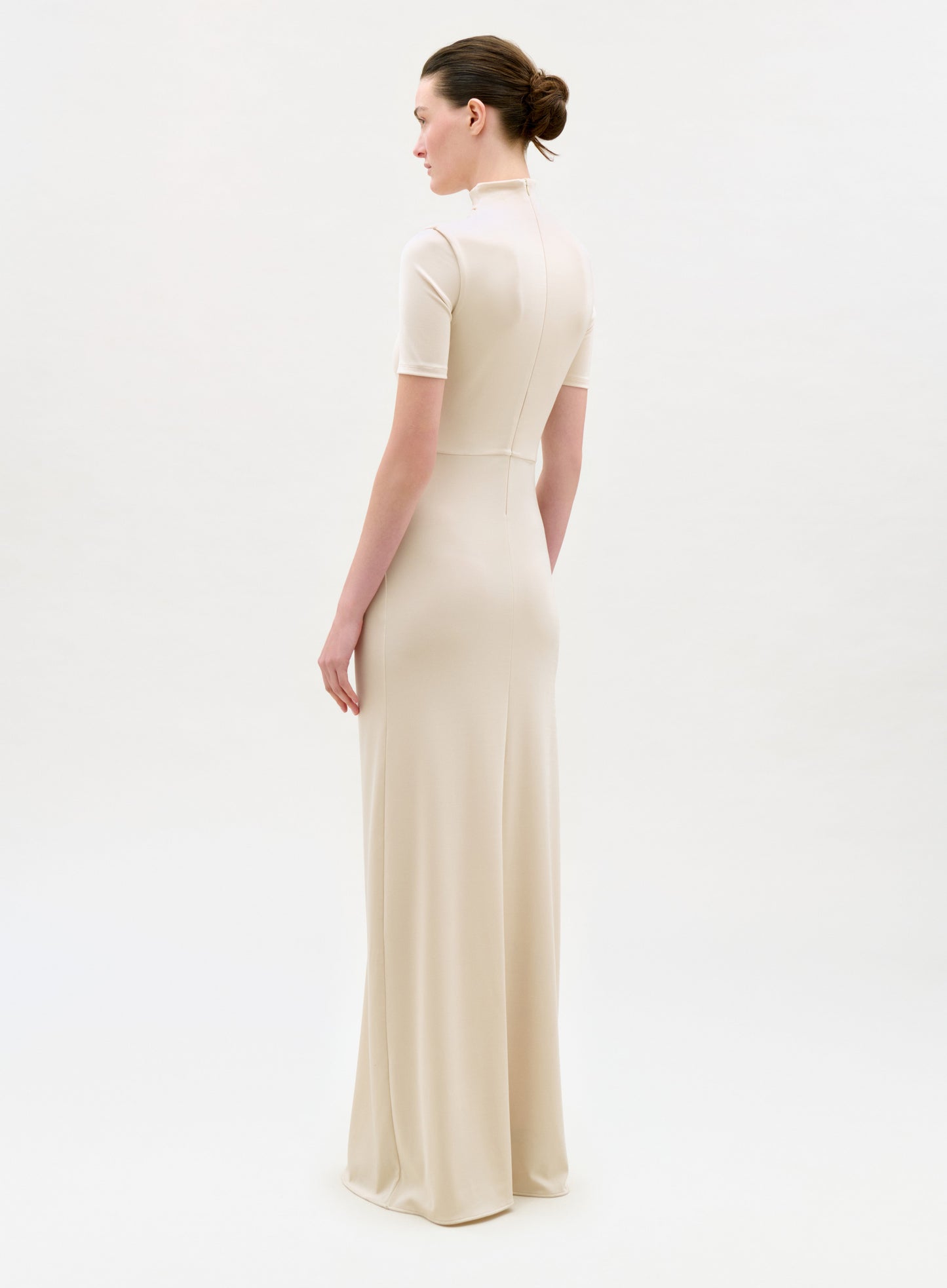 Woman wearing a long beige dress on a white background