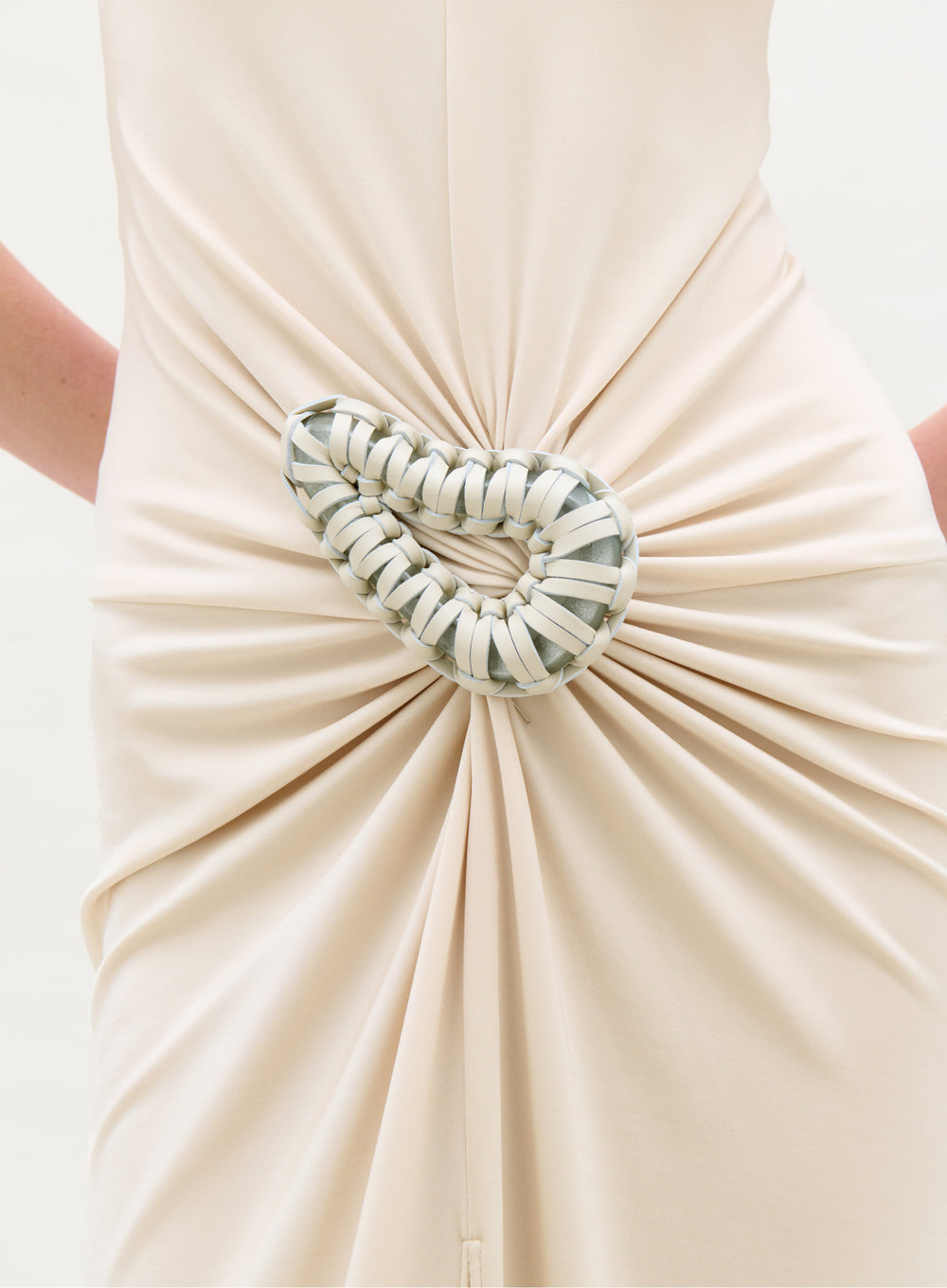 Beige dress with a decorative heart-shaped brooch on a white background