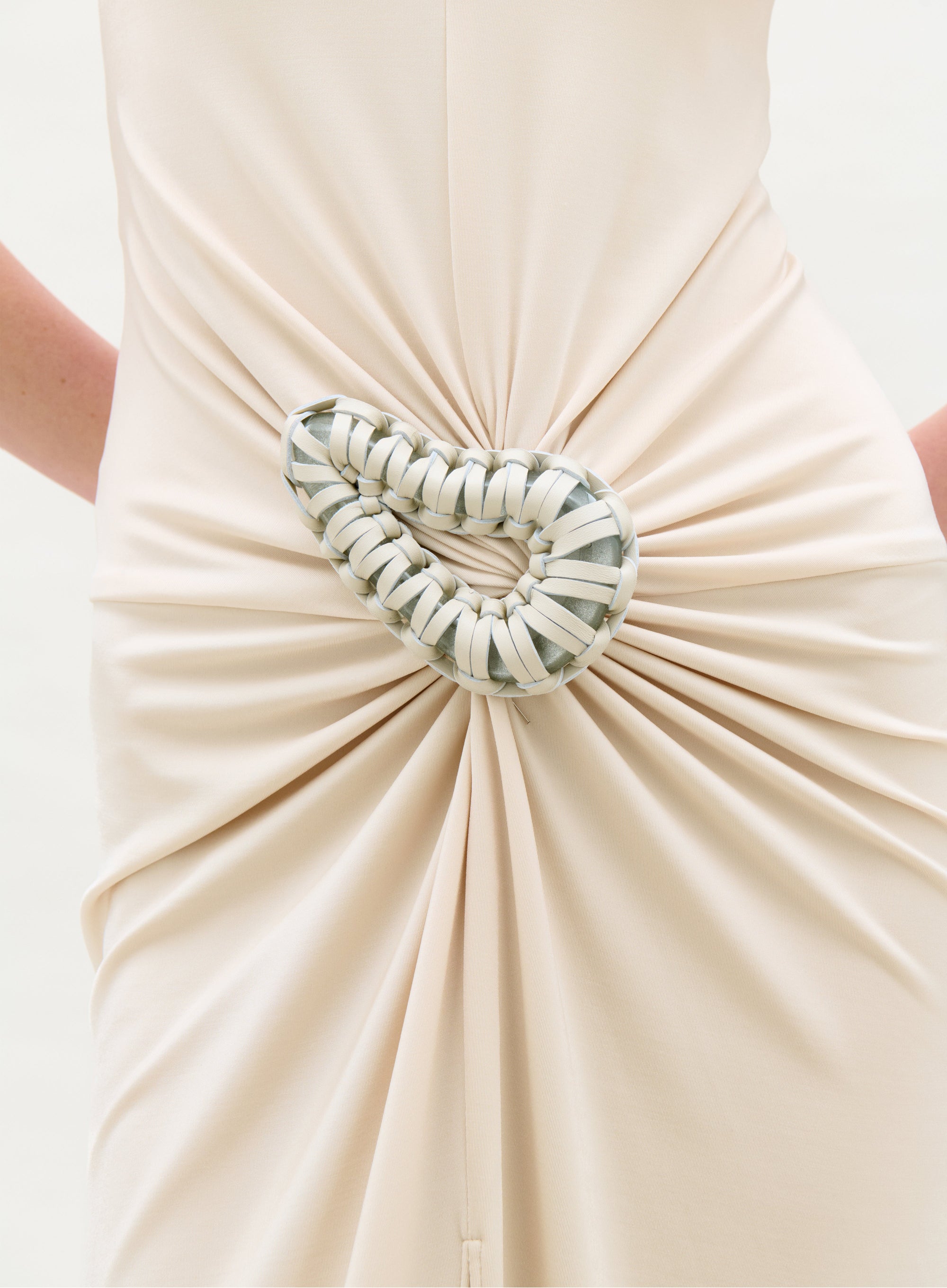 Beige dress with a decorative heart-shaped brooch on a white background