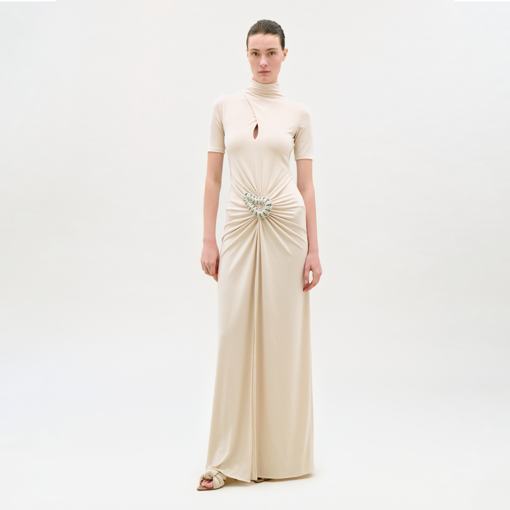 Woman wearing a beige evening gown with a subtle embellishment on a white background