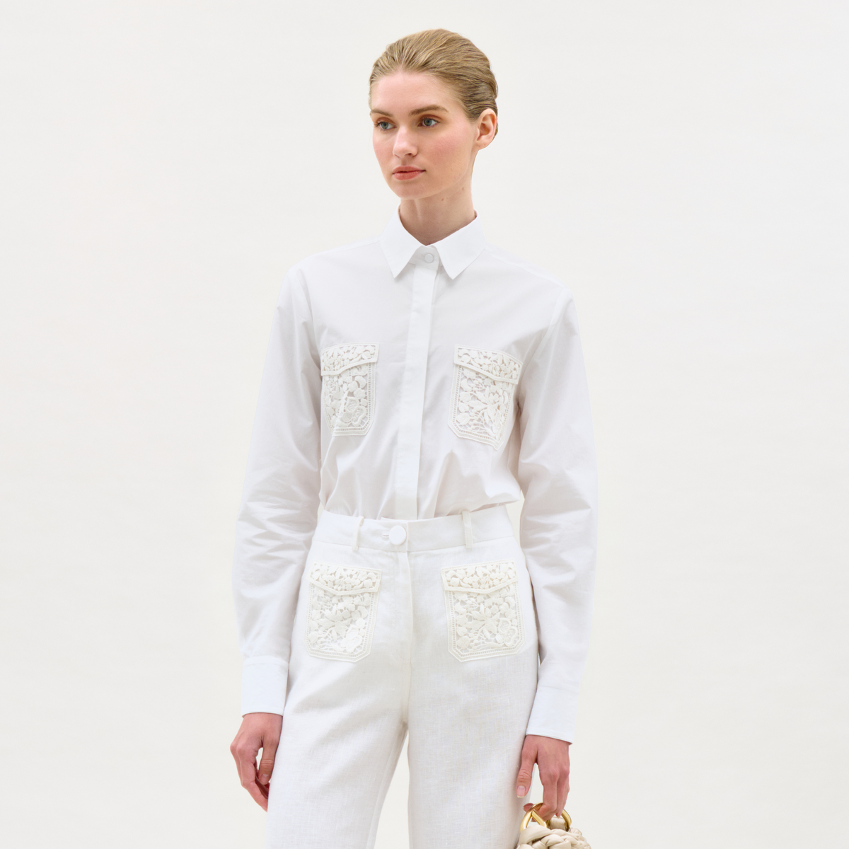Person wearing a white outfit with lace details on a light gray background
