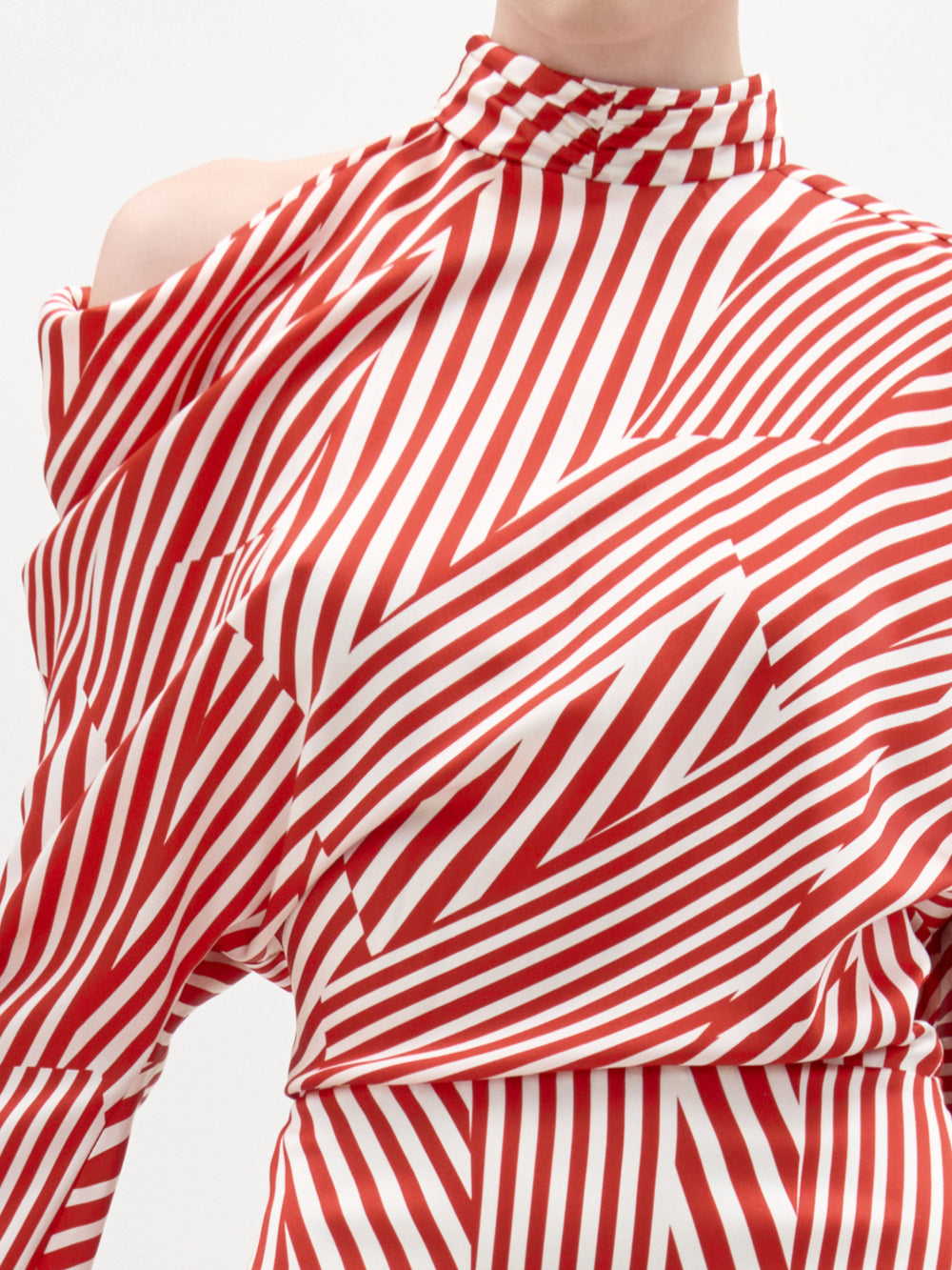 A person models the Lisa Dress by SVT DESIGNS, featuring red and white diagonal stripes, a high neck, Italian fabric, and an asymmetrical shoulder cutout. The cropped image highlights the upper torso and neckline.