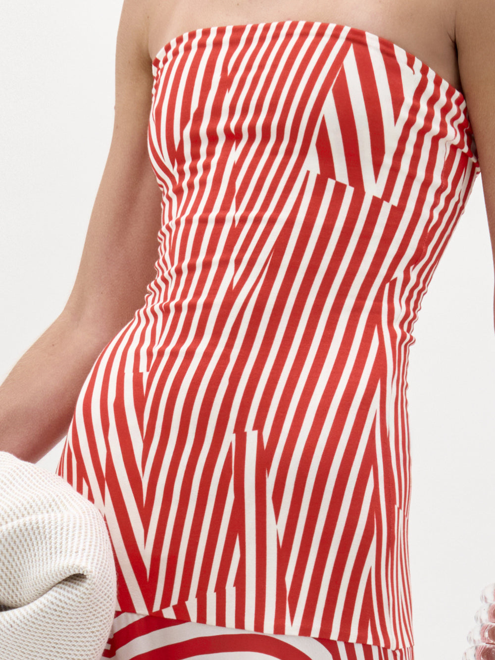 A person models the Muriel Dress by SVT DESIGNS—a strapless maxi with red and white diagonal stripes and a fitted bodice. The photo shows the torso and part of one arm against a plain background.