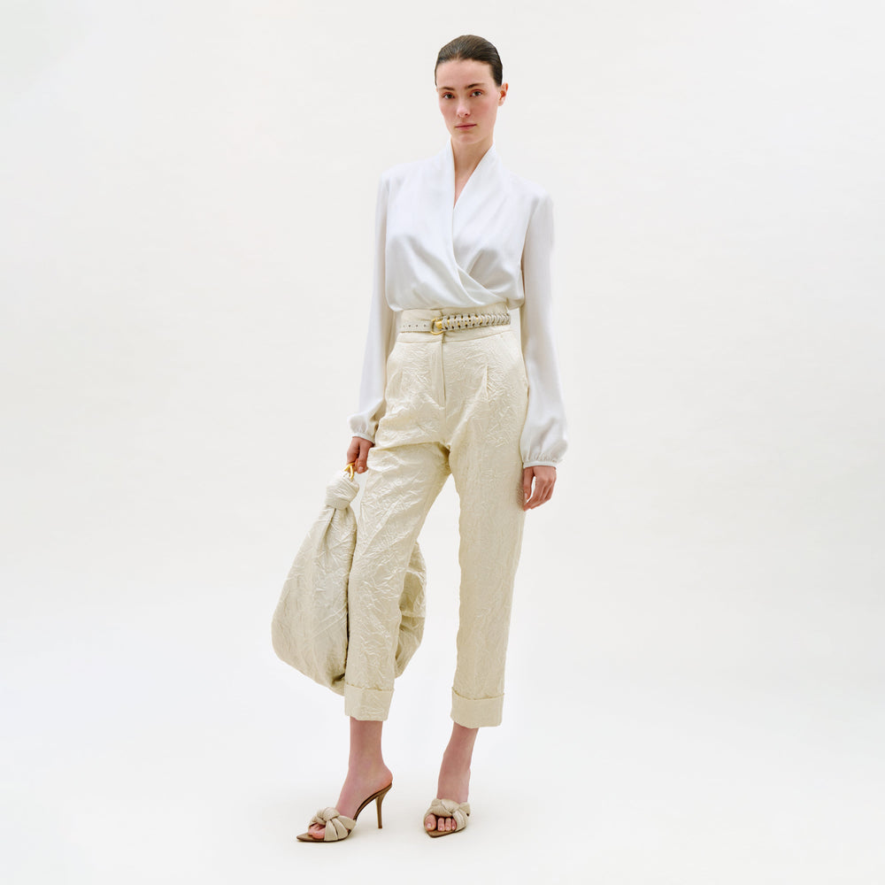 Woman wearing a white blouse and beige pants on a white background