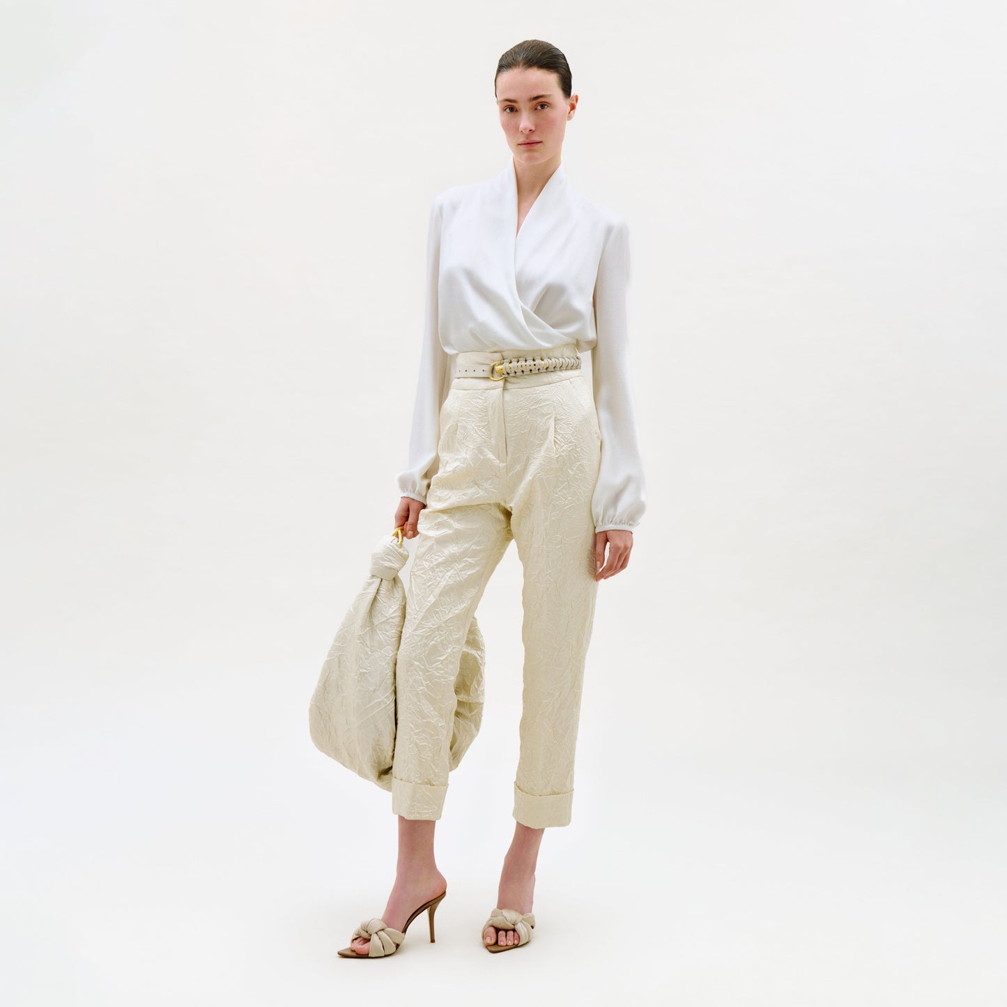 Woman wearing a white blouse and beige pants on a white background