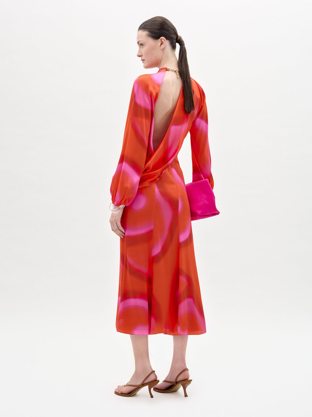 Woman wearing a vibrant red and pink dress with a white background