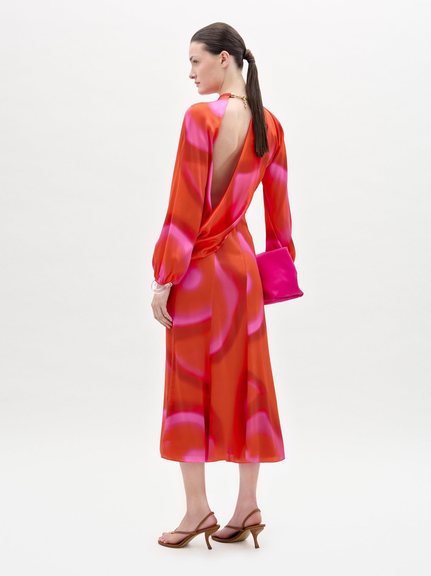 Woman wearing a vibrant red and pink dress with a white background