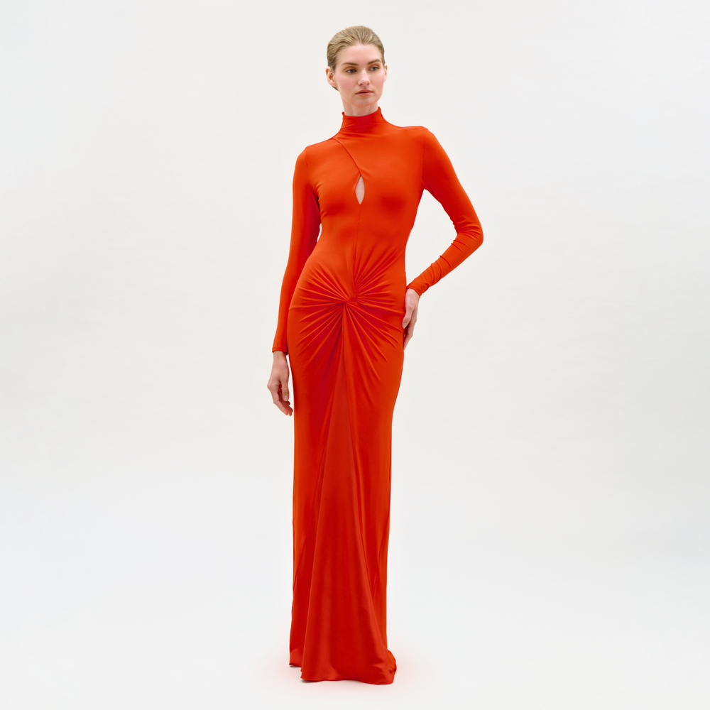 Woman wearing a long orange dress with a high neckline on a white background