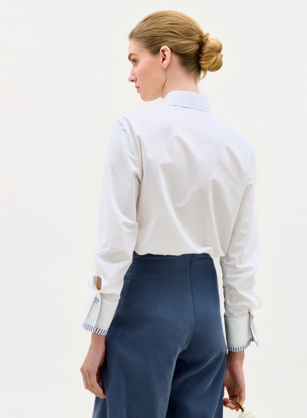 Woman wearing a white shirt and blue pants on a plain background