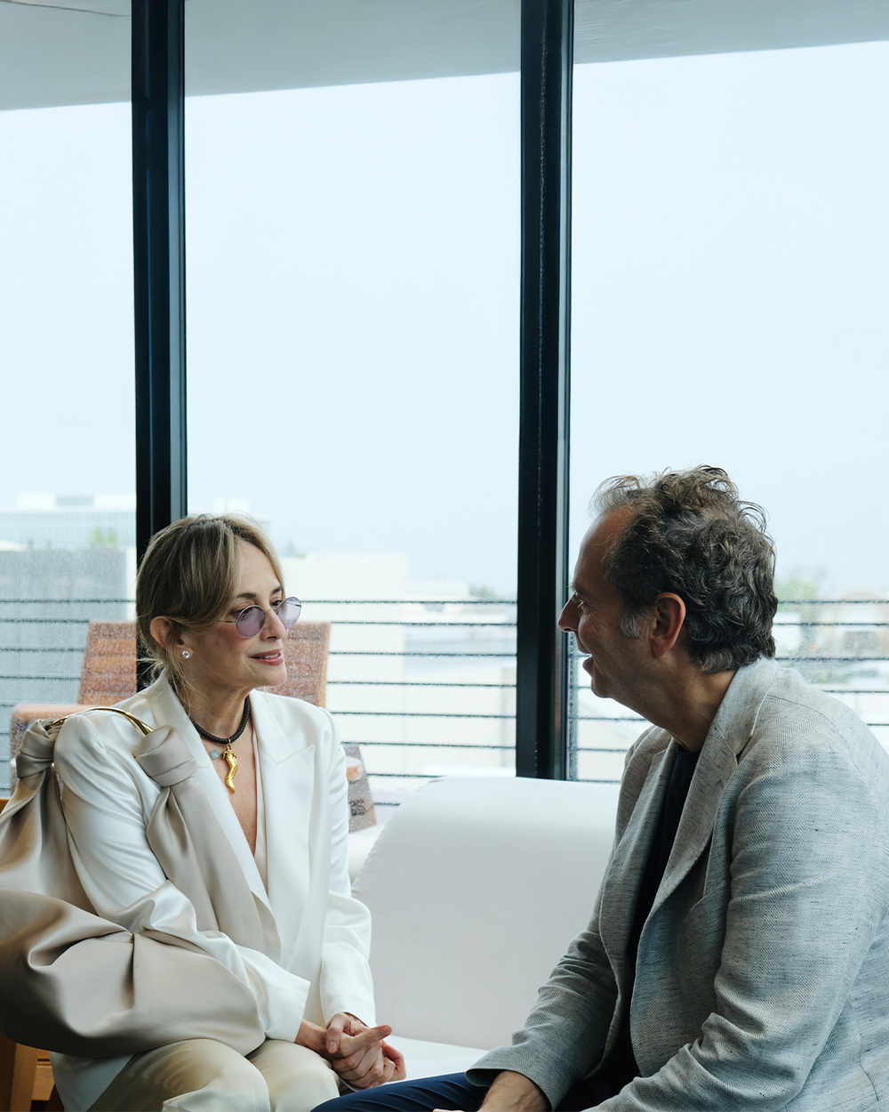 Two people sitting in a modern office setting with large windows.