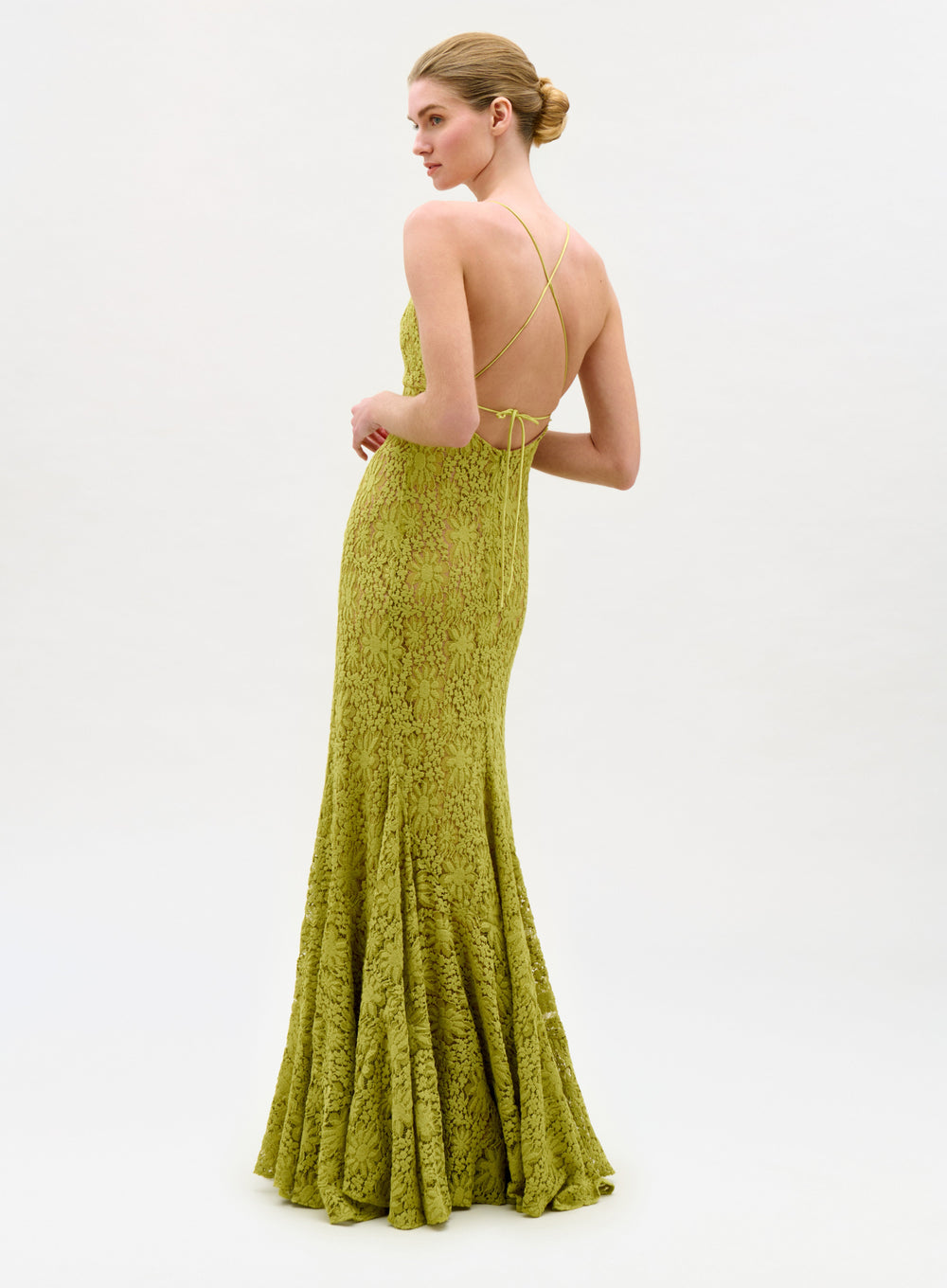 Woman wearing a green lace evening gown on a white background
