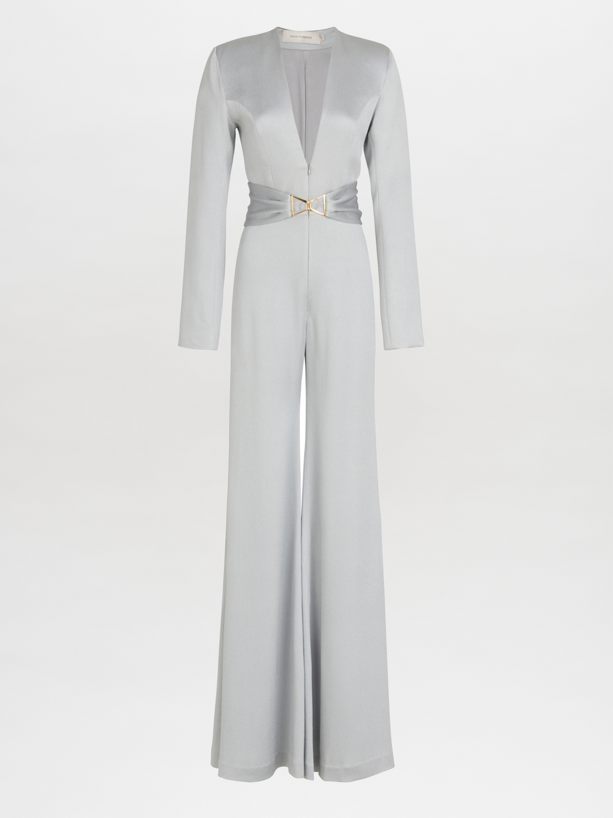 The Taboa Jumpsuit Gray by Silvia Tcherassi is a full-length, long-sleeved silk outfit featuring a deep V-neck and a belted waist with metallic clasp detail. Its flared legs create a wide-leg silhouette against the plain white background.