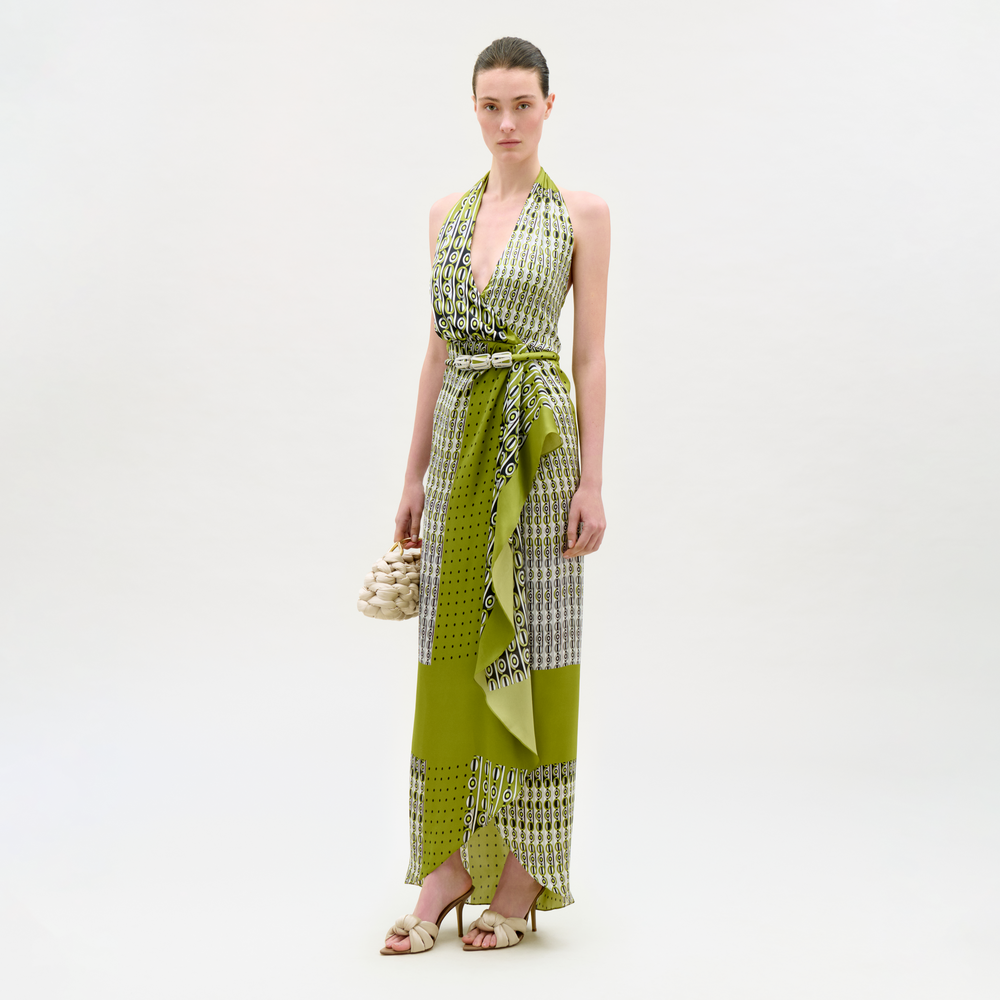 Woman wearing a green and white patterned dress with a matching scarf on a white background