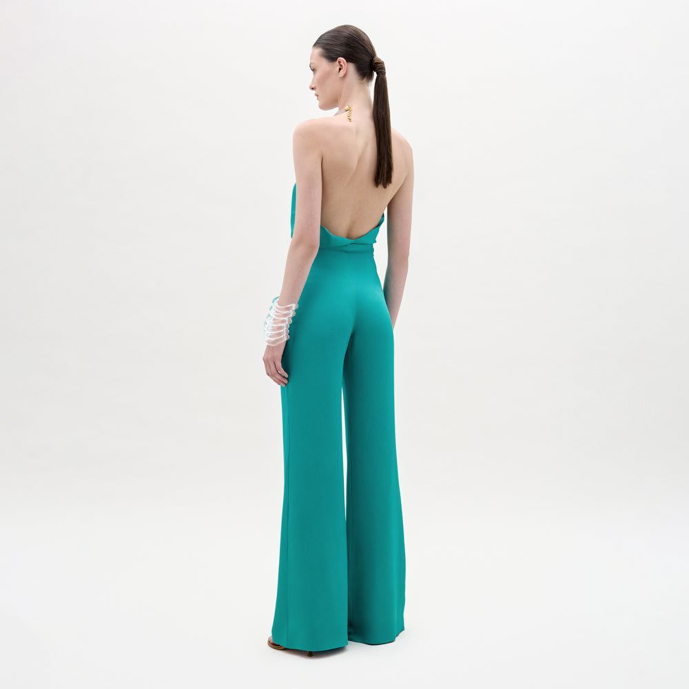 Woman wearing a teal jumpsuit with a white background