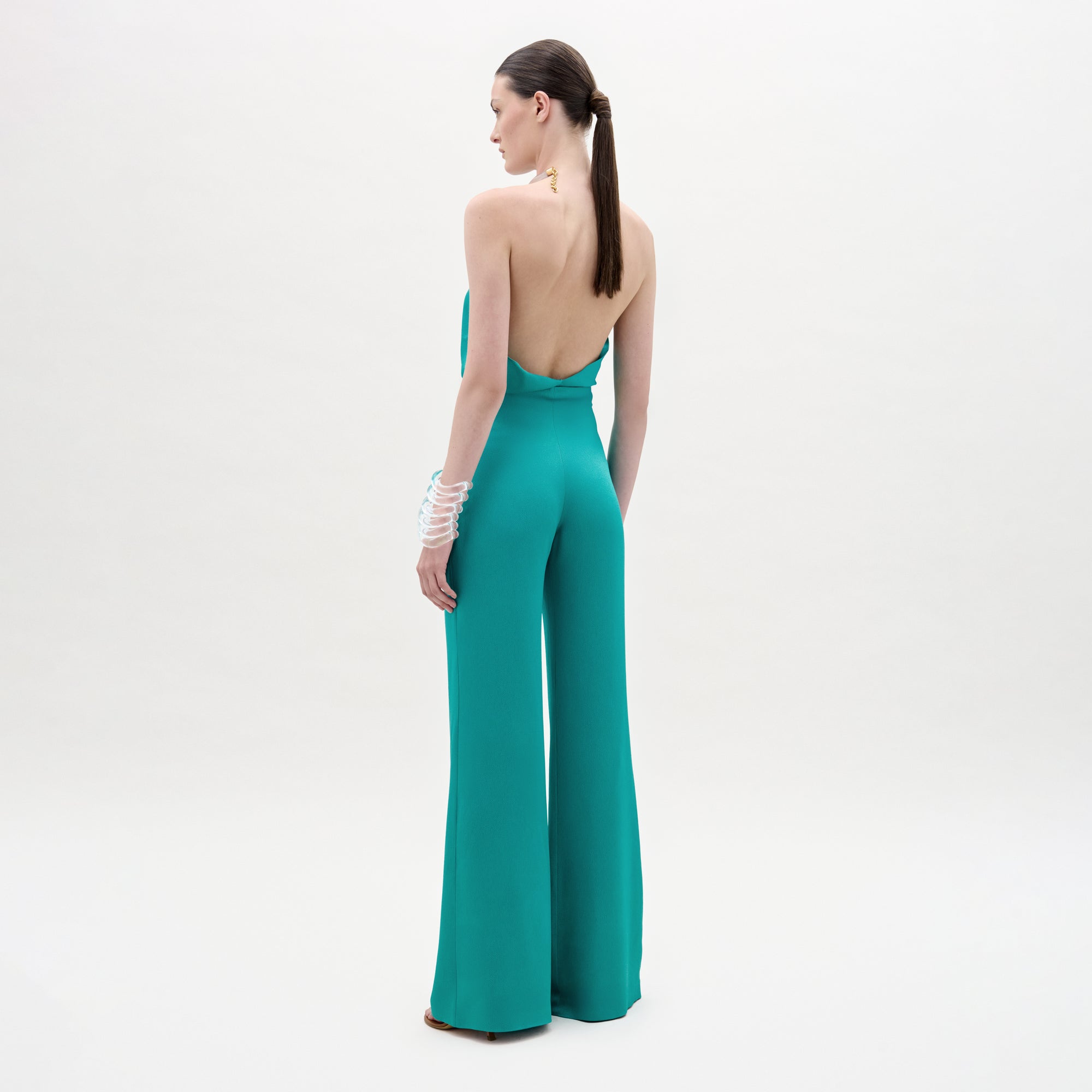 Woman wearing a teal jumpsuit with a white background