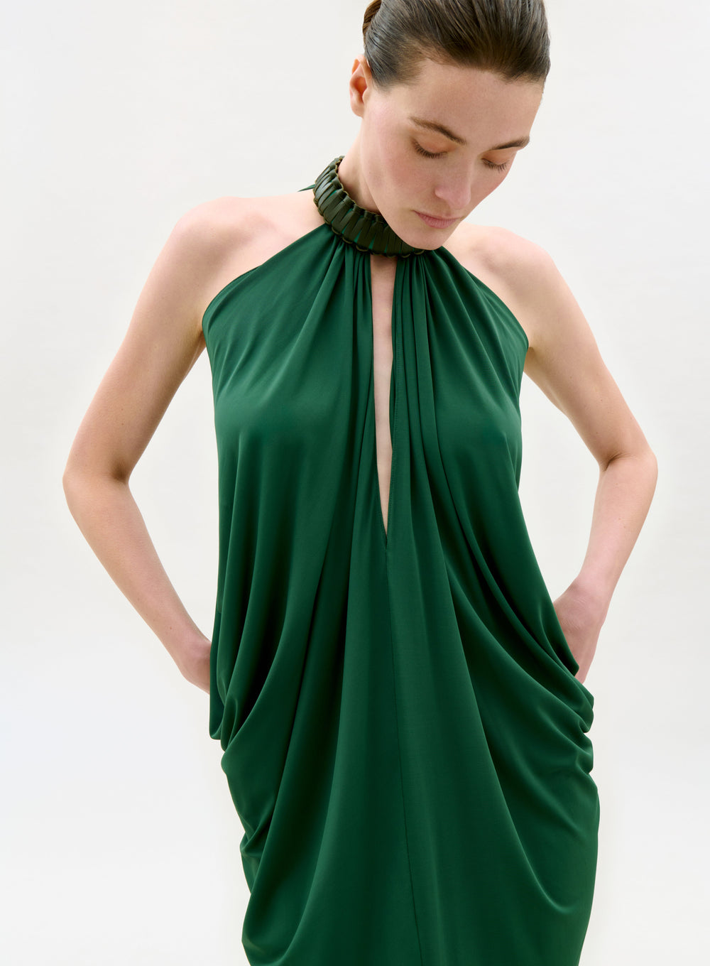Woman wearing a green halter neck dress against a white background