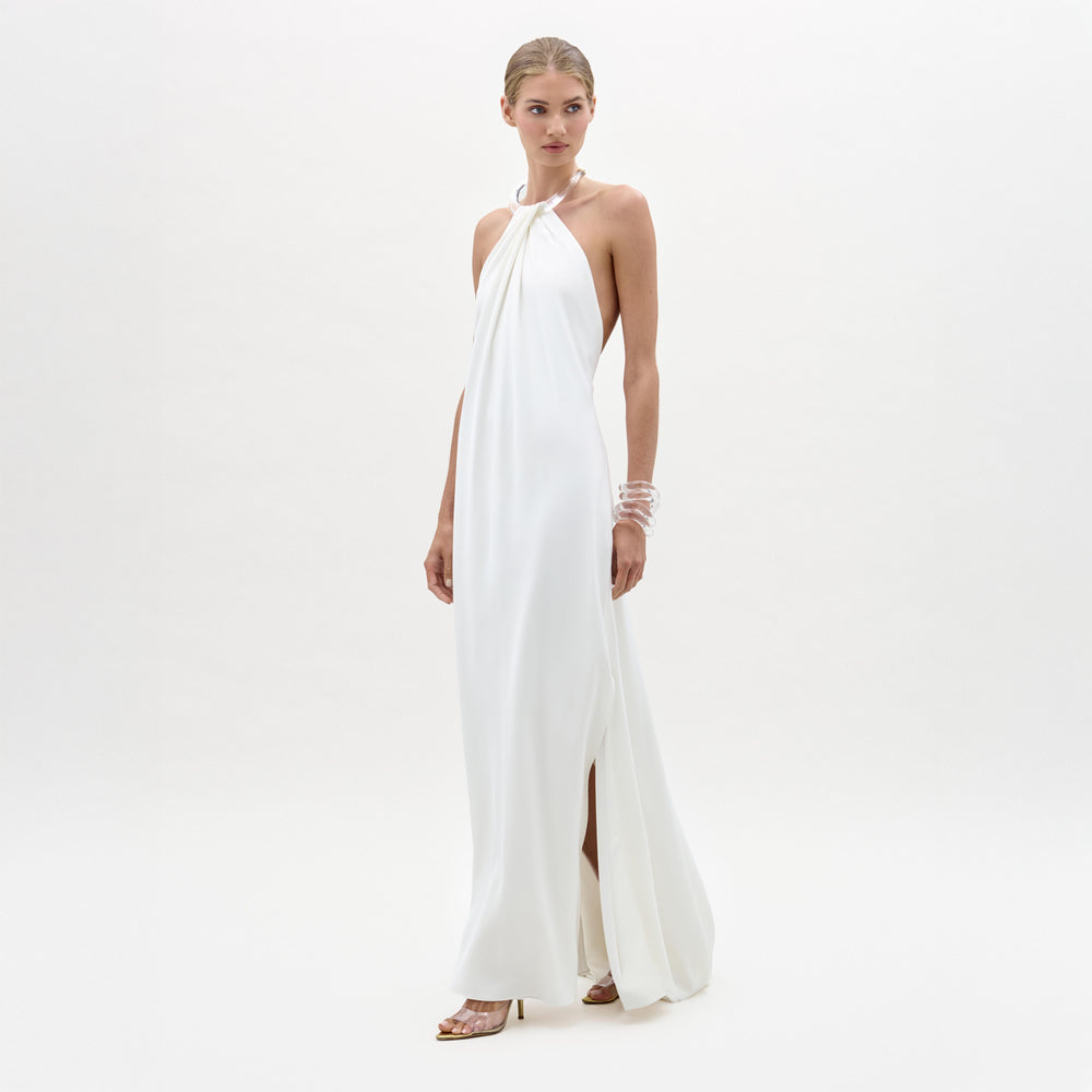 Woman wearing a white halter neck gown on a plain background