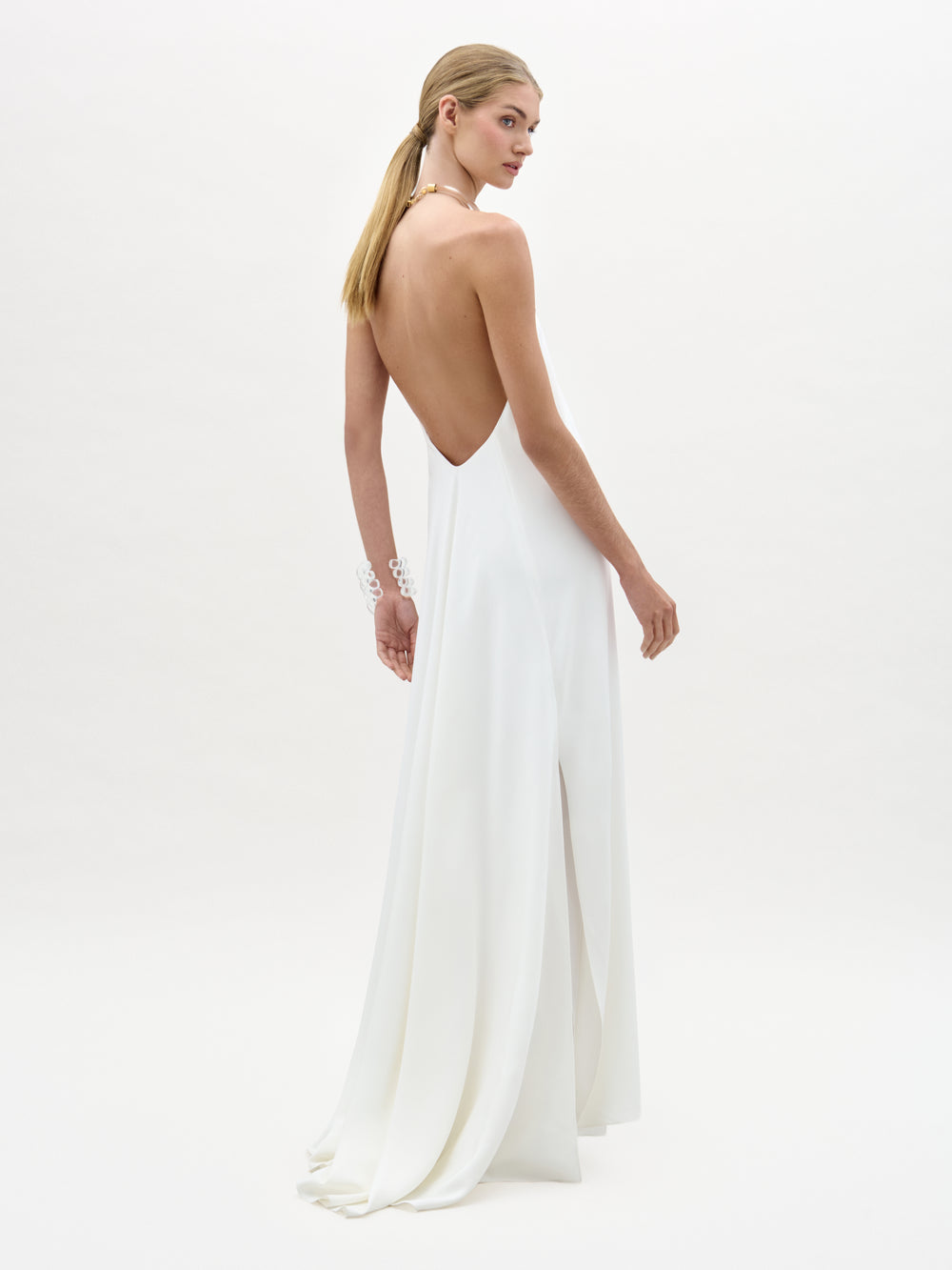 Woman wearing a white open-back dress on a plain background