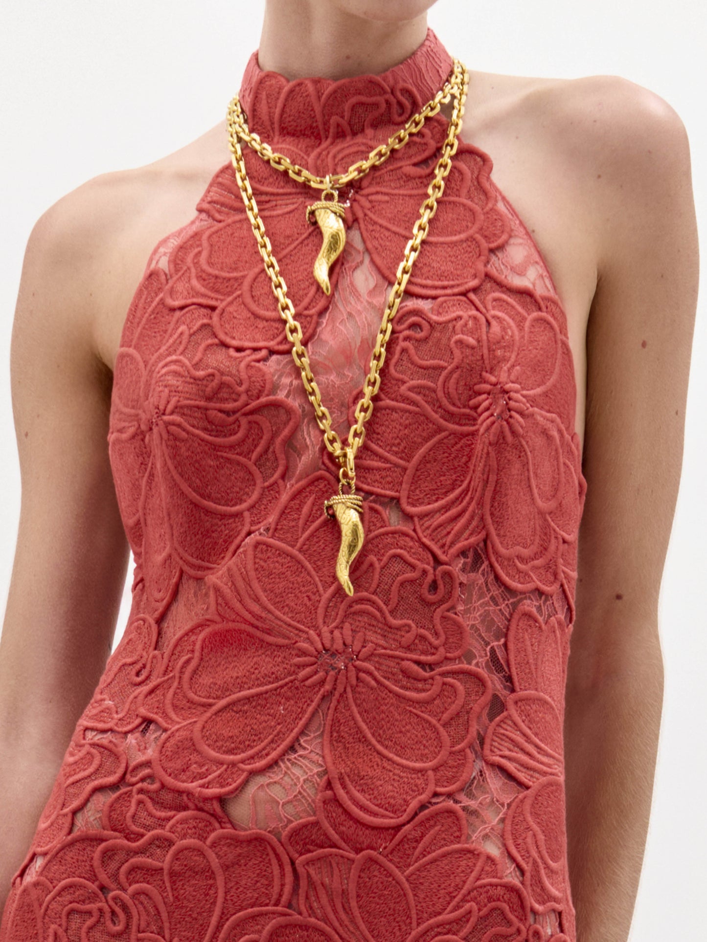A woman wearing the floor-length, sleeveless Mab Dress with a high neckline and layered gold necklaces, standing against a plain white background.