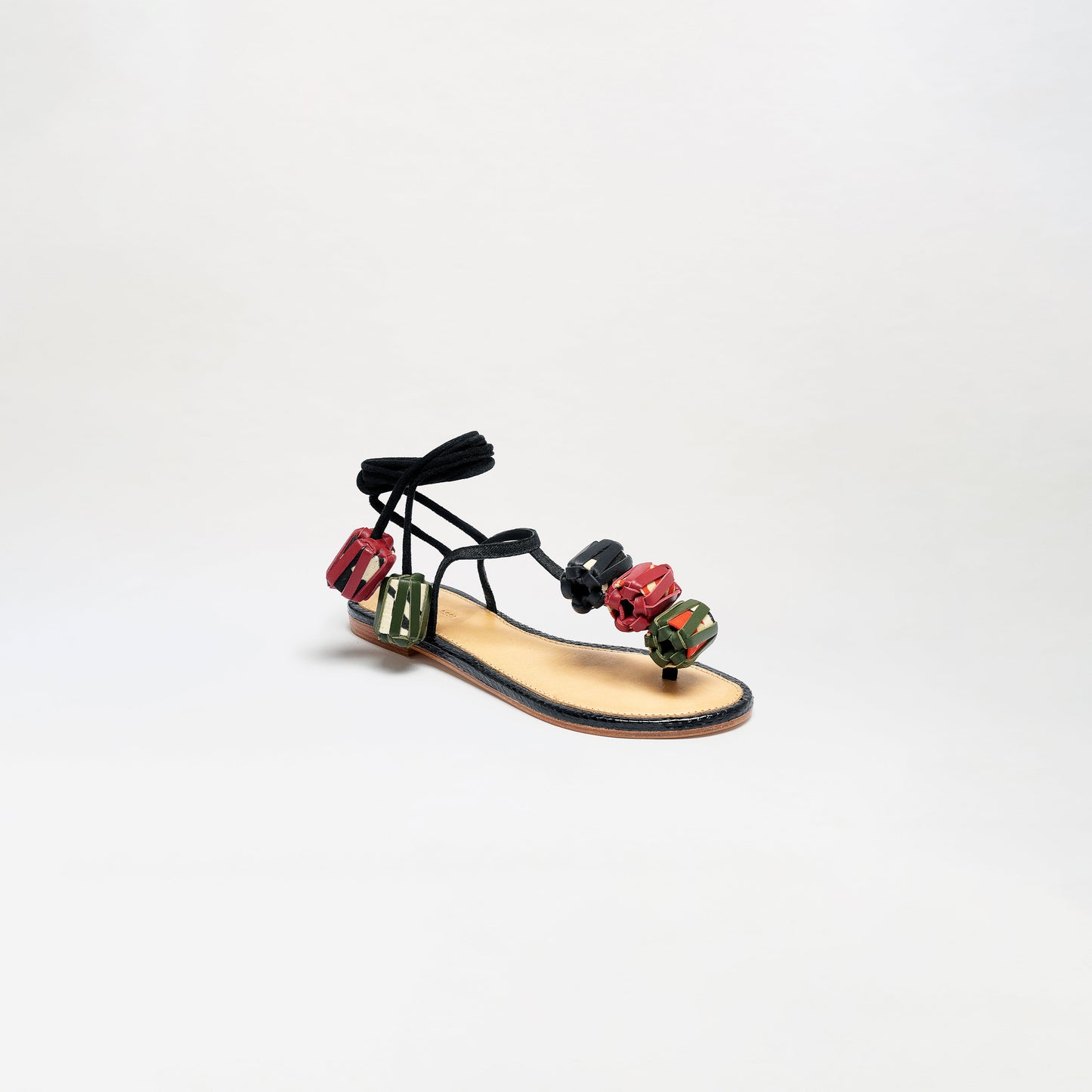 The Elvira Sandals feature black laces, a tan sole, and straps adorned with vibrant geometric red and green decorations, shown against a plain white background.
