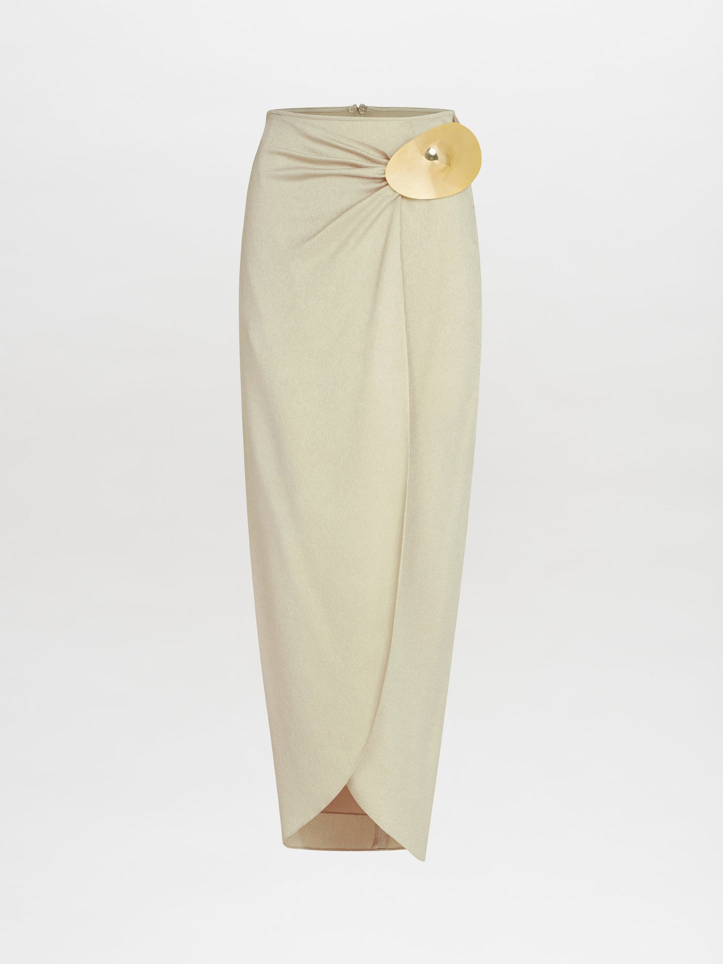 The Adrianne Skirt by SVT DESIGNS is a beige high-waisted midi crafted from hammered satin, featuring a draped design with a gold-tone embellishment at the waistband. Its elegant front overlap and long length create a sophisticated look against a plain background.