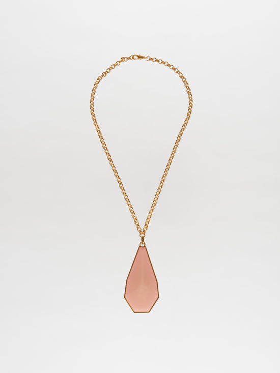 The Ascoli Necklace by Silvia Tcherassi, featuring a gold chain and geometric teardrop-shaped pink pendant, is elegantly showcased on a plain white background. Ideal for any occasion, this exquisite piece ensures swift shipping and minimal processing time for your convenience.