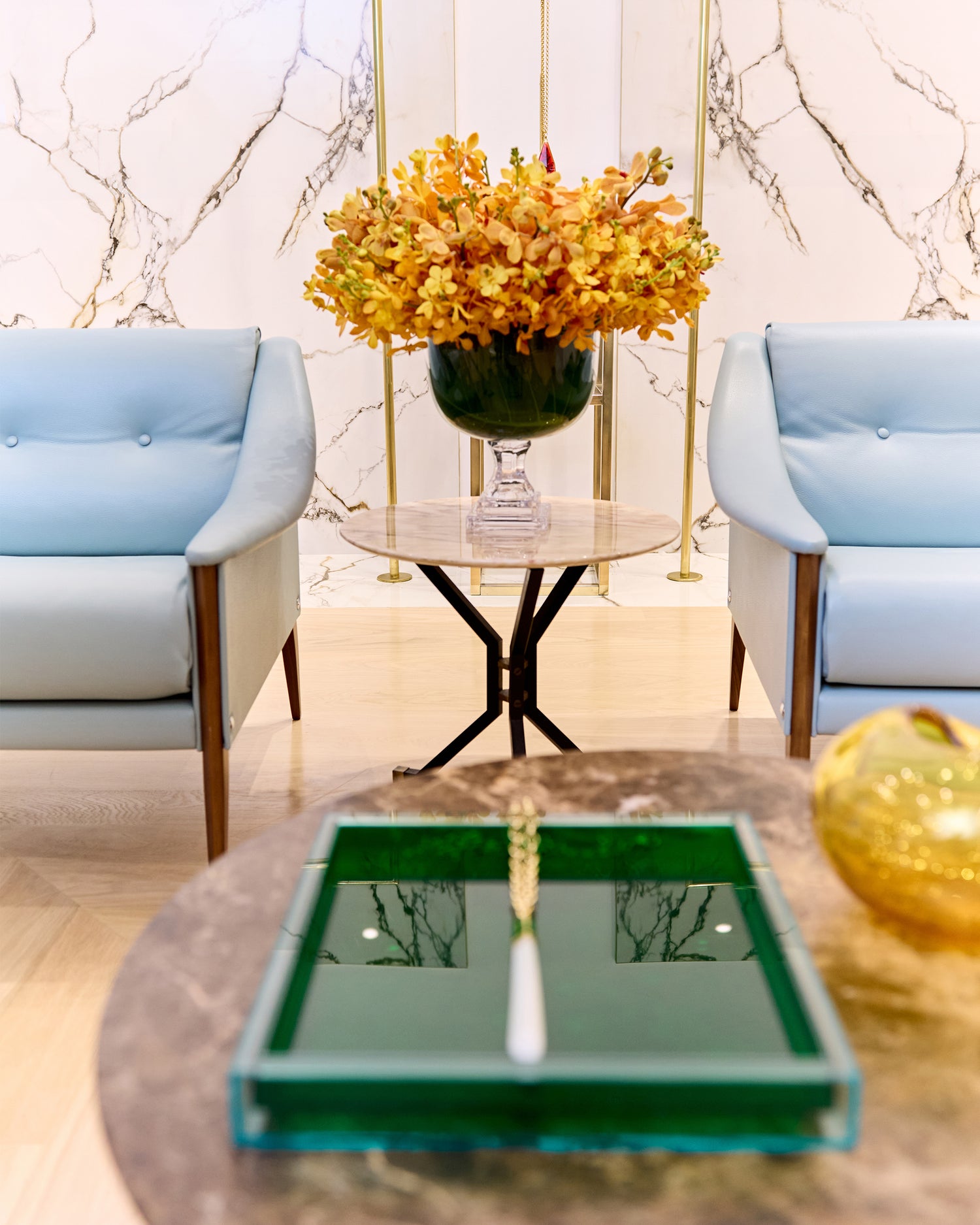 Bal Harbour Boutique Store Image. There is a base with flowers and two blue chairs.