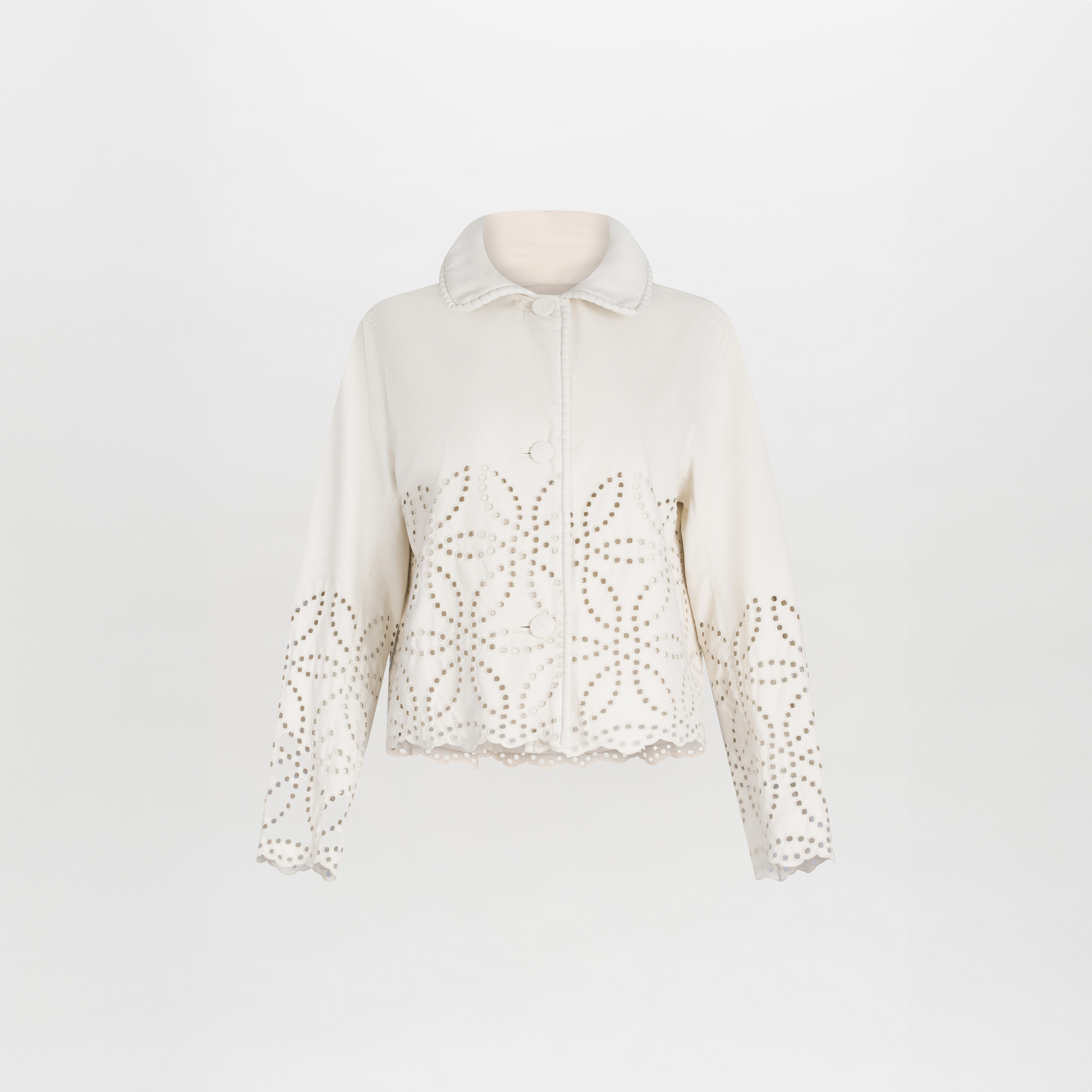 The Belen Jacket from SVT DESIGNS is a cream-colored novelty piece with button closures, featuring a rounded collar and intricate cut-out patterns on the sleeves and hem, made from embroidered ecoleather for an elegant look.