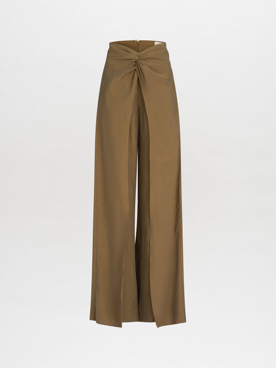 The Canturipe Pant by SVT DESIGNS is a pair of brown high-waisted pants made from luxurious Italian fabric, featuring a wide leg silhouette and front knot detail, set against a plain white background.