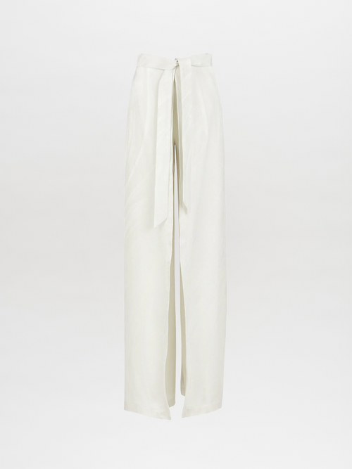 The Cibeles Pant Moonstone by Silvia Tcherassi features high-waisted, wide-leg white satin with a long tie belt, crafted from moonstone jacquard for a minimalist look against a plain background.