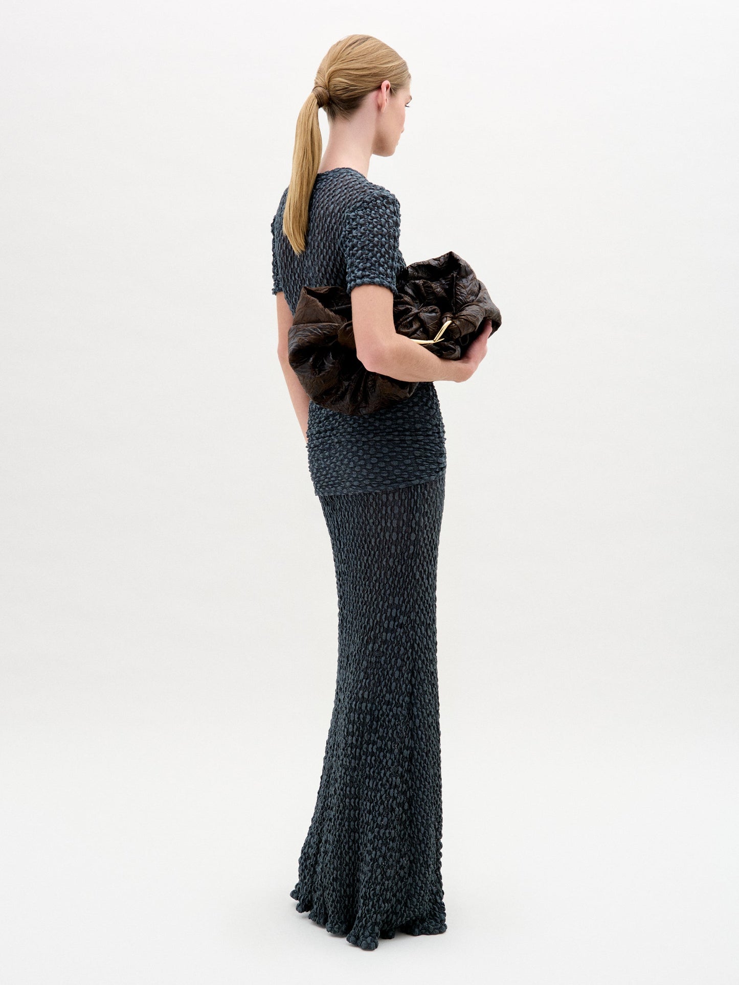 A woman wearing the Ciji Skirt in color Deep Gray with a Sofia Bag Maxi in color Cacao on a white background.