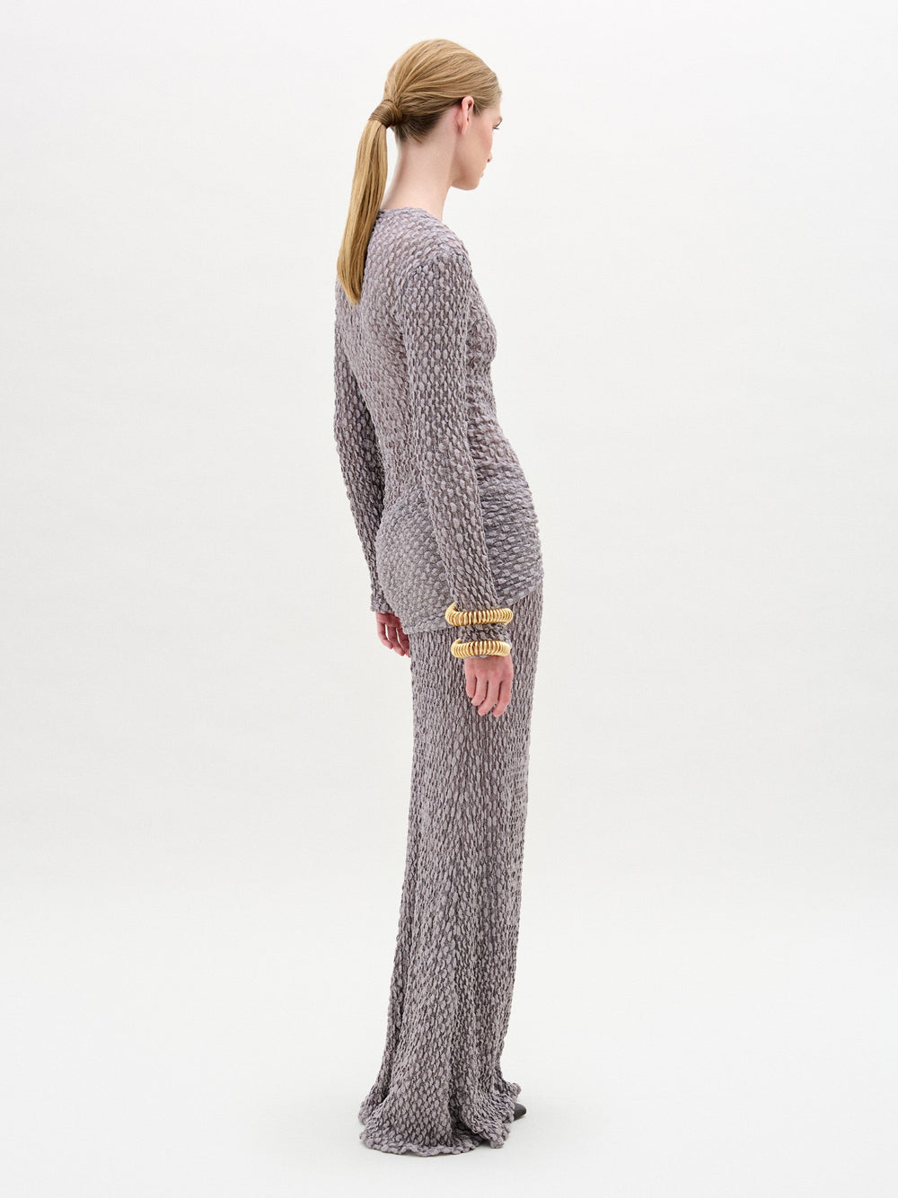 A woman wearing the Ciji Skirt  in color Gray with a Golden bracelet on a white background.