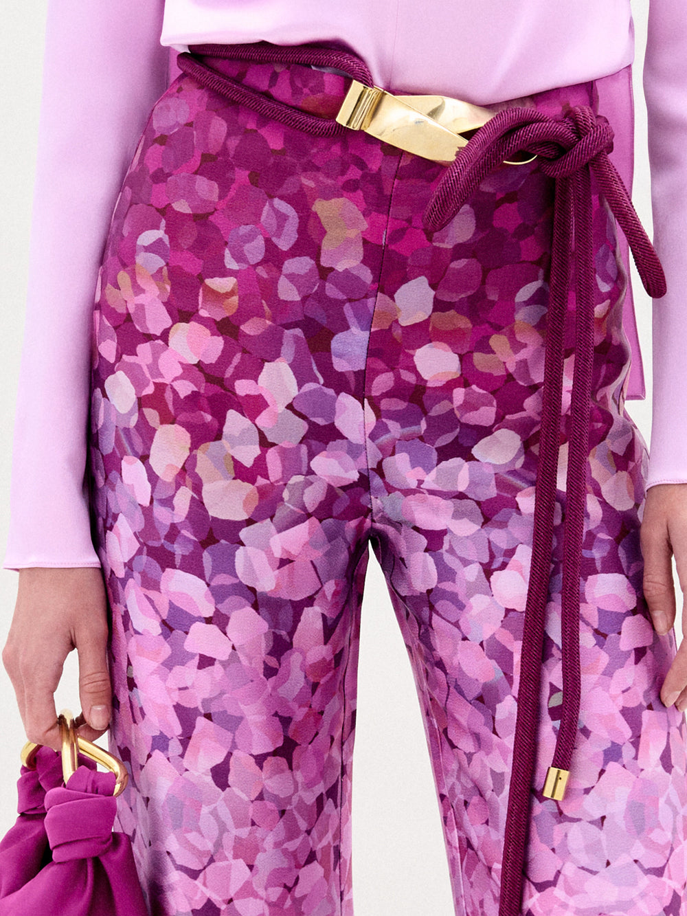 A woman wearing the Como Pant in color Magenta with a Sofia bag in color Purple on a white background.