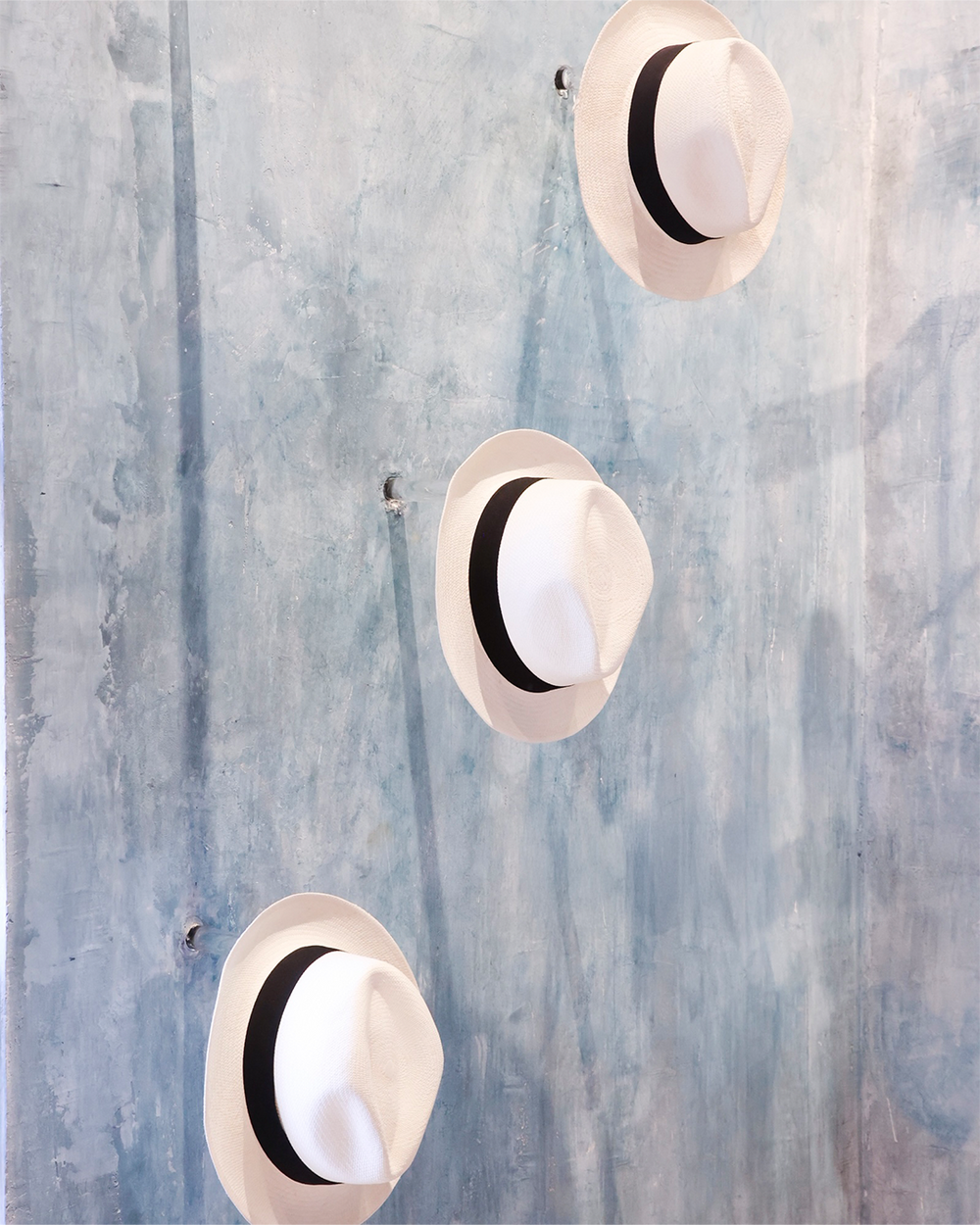 Three round wall lights with black accents on a textured blue wall.