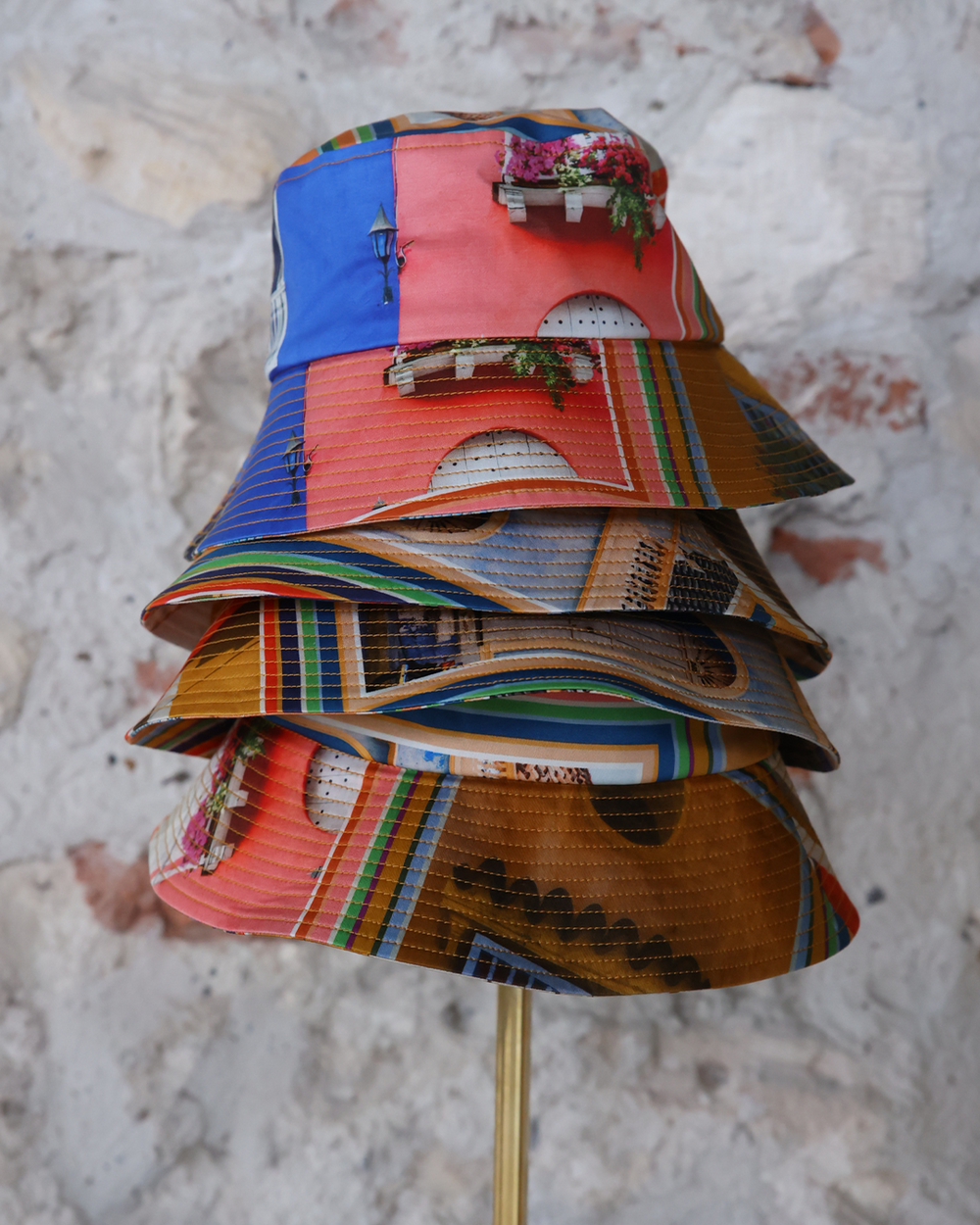 Colorful layered fabric dress on a mannequin against a textured wall.