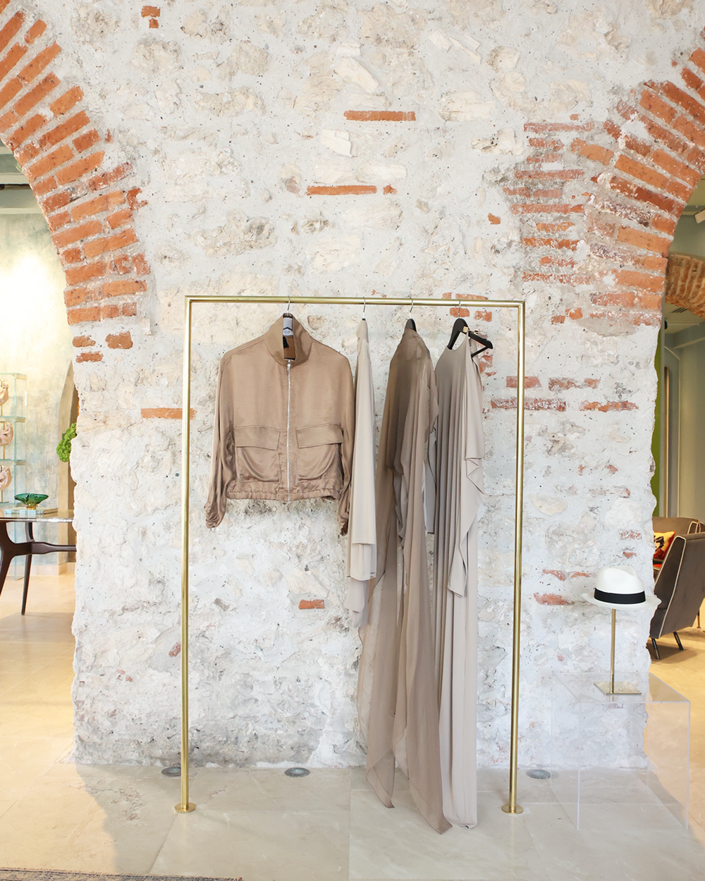 Clothing rack with jackets against a textured brick wall.