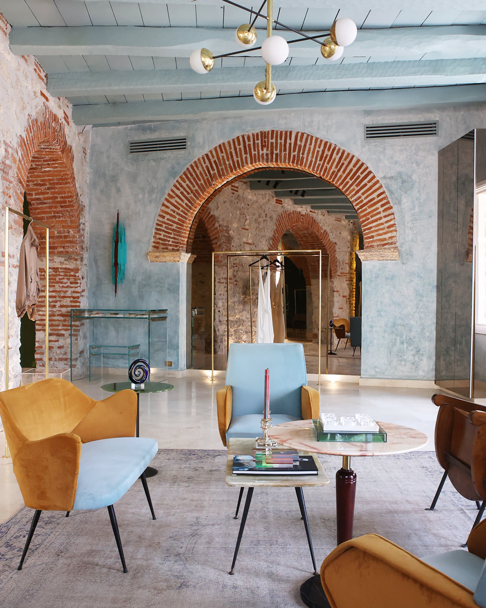 Modern interior with colorful chairs and a round table in a room with exposed brick walls.