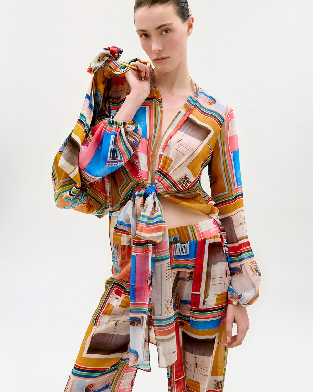 Model wearing a colorful striped outfit with a scarf on a white background