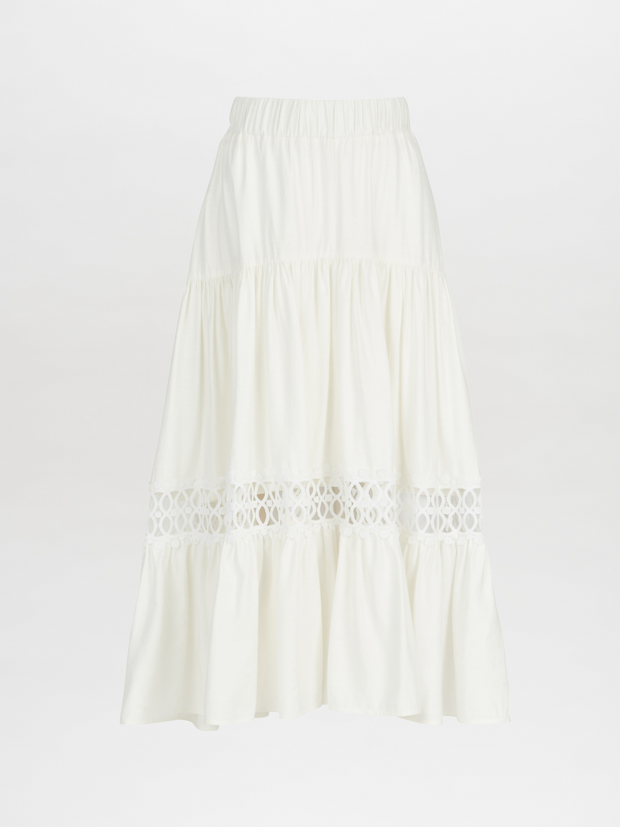 The Cher Skirt White by SVT Designs is an ankle-length, white viscose skirt featuring a tiered design on a plain background, highlighted by its elastic waistband and a decorative lace trim panel in the middle for an added elegant flair.