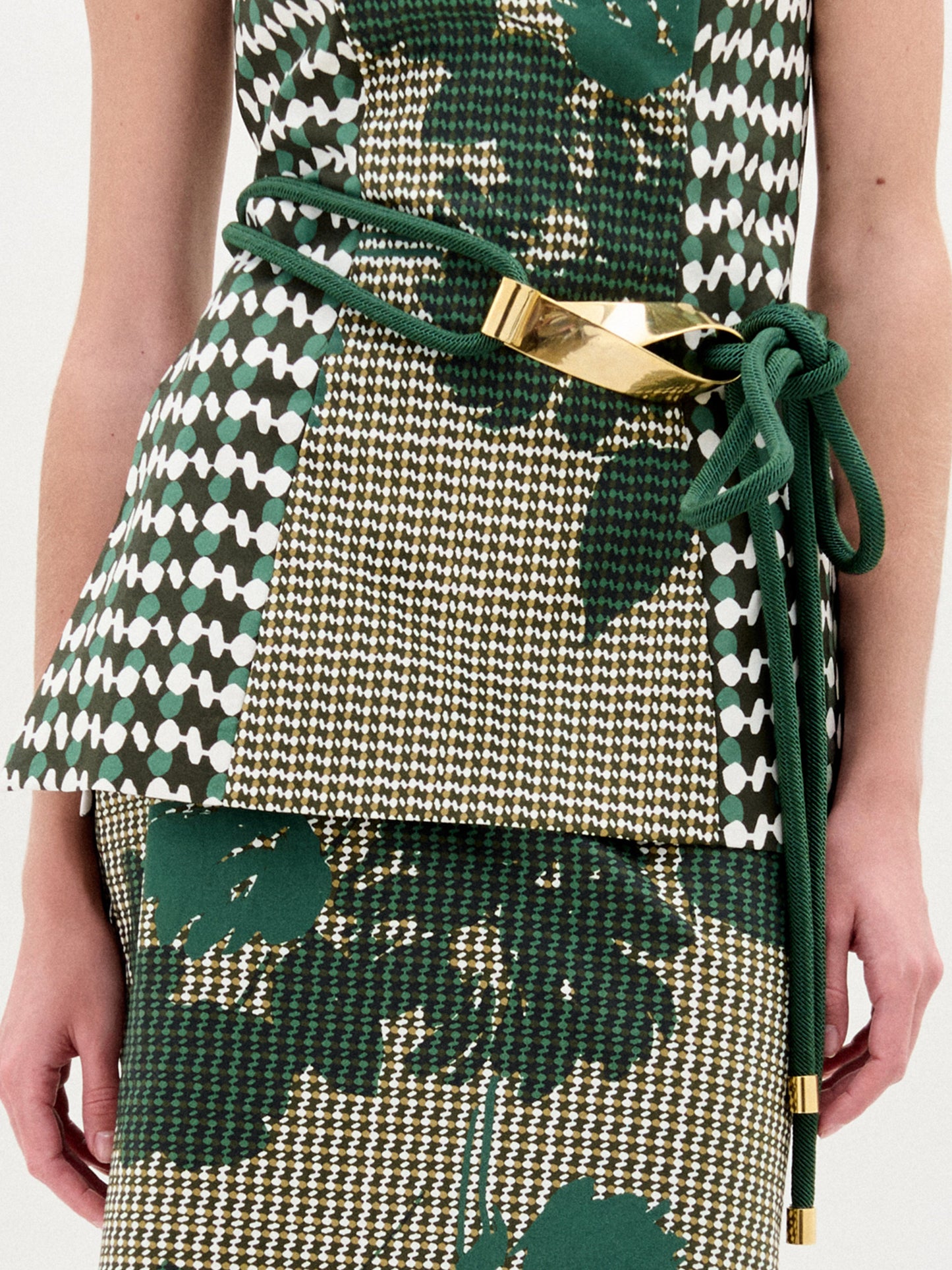 A person wears SVT DESIGNS' Daiana Belt over a patterned green, white, and gold outfit, standing against a light background.