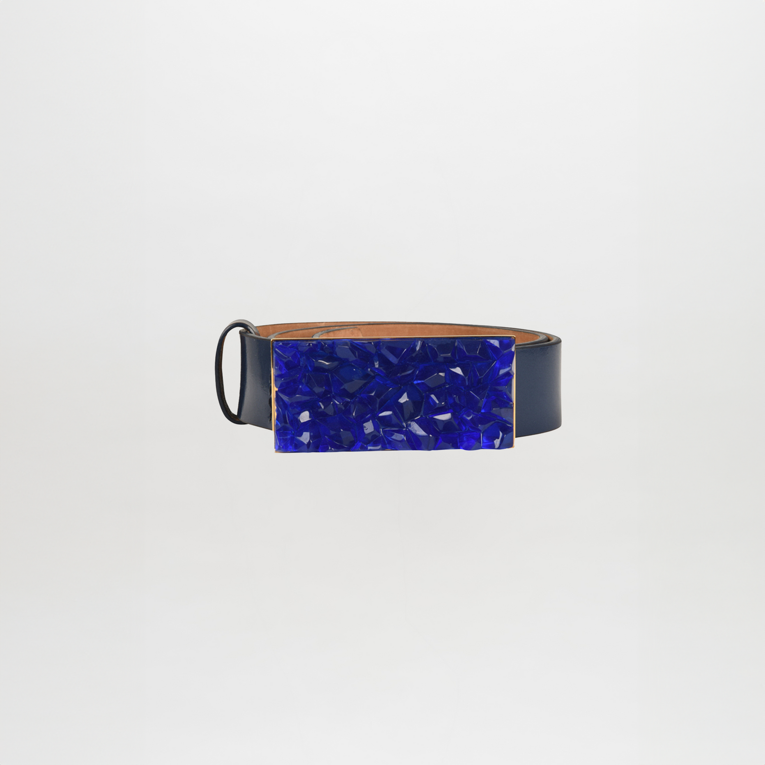 The Dora Belt by SVT DESIGNS features a black leather strap with a deep blue, textured Italian resin buckle showcasing intricate mosaic-like patterns. Its polished finish creates a patent leather effect, set against a plain white background for striking contrast.