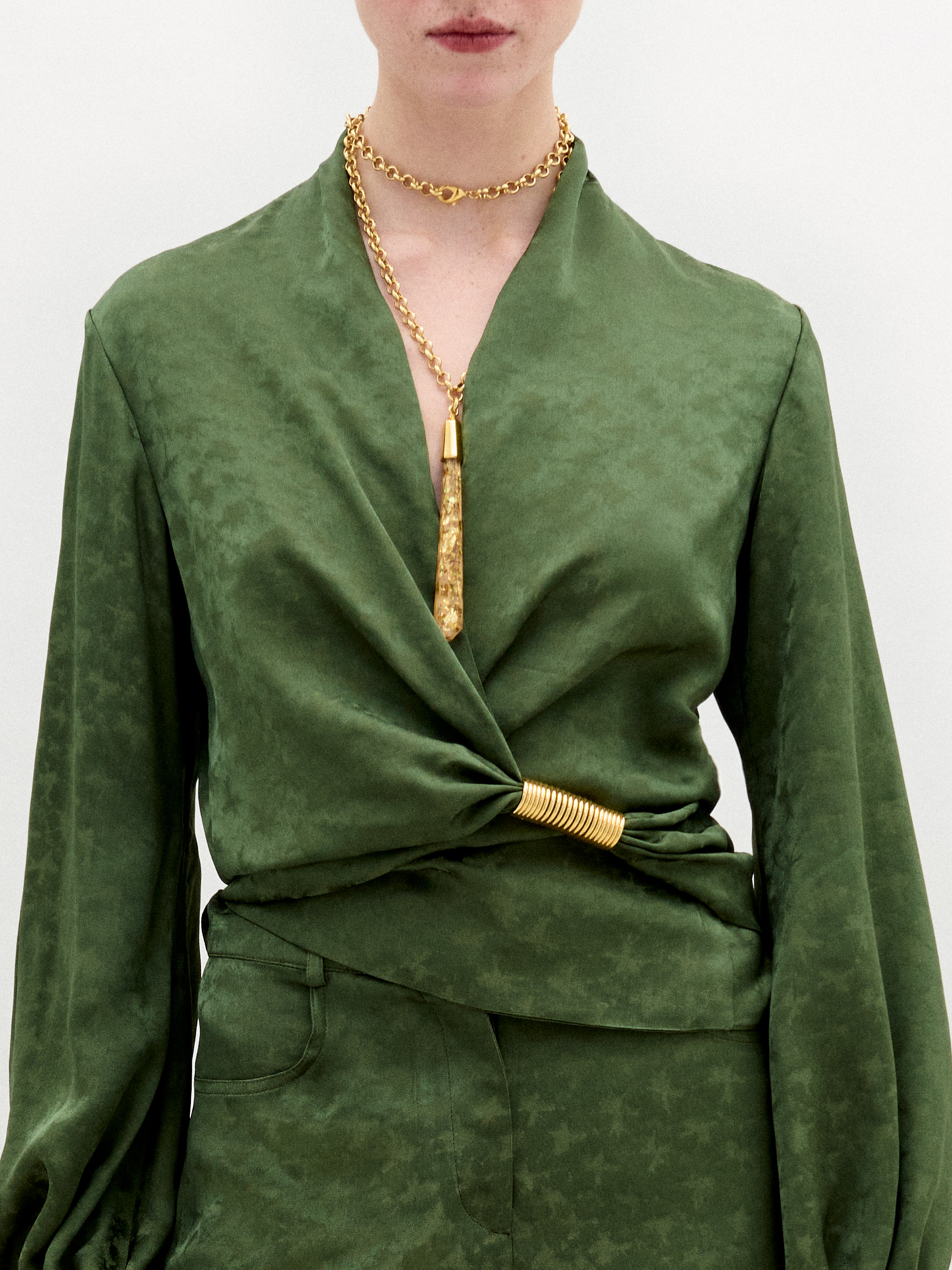 Green outfit with a gold necklace on a white background