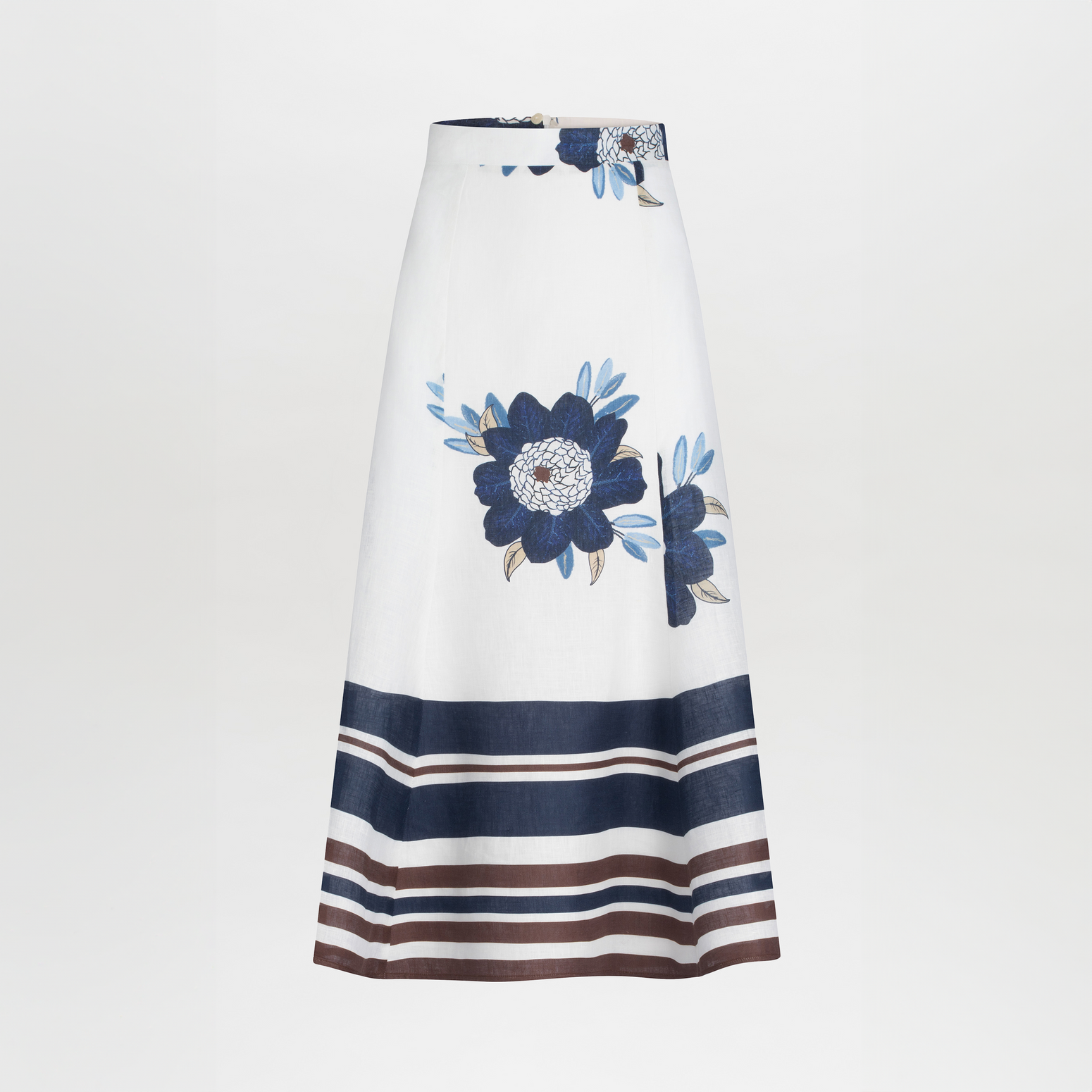 The Erin Skirt by SVT DESIGNS is a high-waisted midi skirt made of 100% cotton, featuring large blue floral prints near the waist, and navy, brown, and white horizontal stripes at the hem on a plain white A-line design.