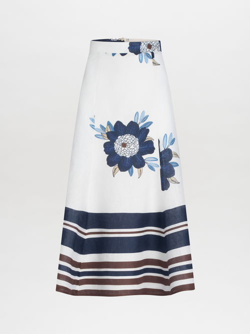 The Erin Skirt by SVT DESIGNS is a high-waisted midi skirt made of 100% cotton, featuring large blue floral prints near the waist, and navy, brown, and white horizontal stripes at the hem on a plain white A-line design.