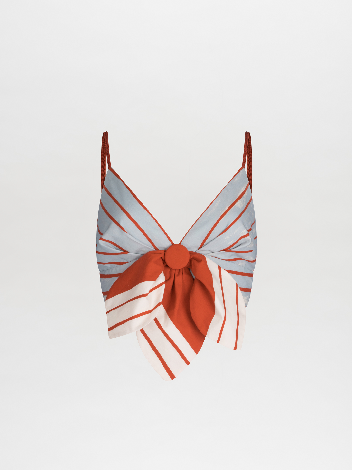 The Flor Top by SVT DESIGNS is a sleeveless cropped top with spaghetti straps, featuring a blue and red striped pattern on a plain background, along with a large central bow accented in red, white, and blue stripes.