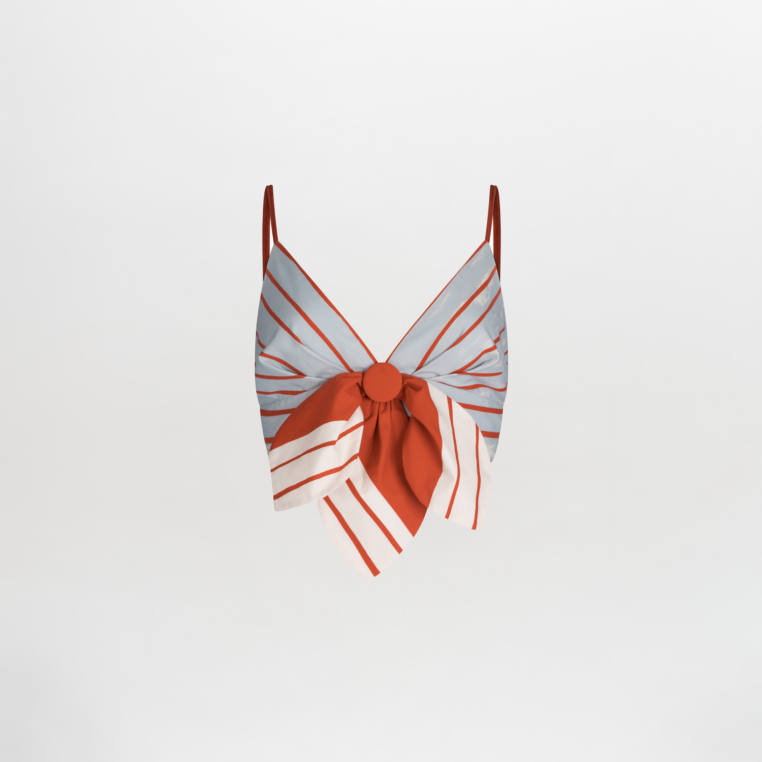 The Flor Top by SVT DESIGNS is a sleeveless cropped top with spaghetti straps, featuring a blue and red striped pattern on a plain background, along with a large central bow accented in red, white, and blue stripes.